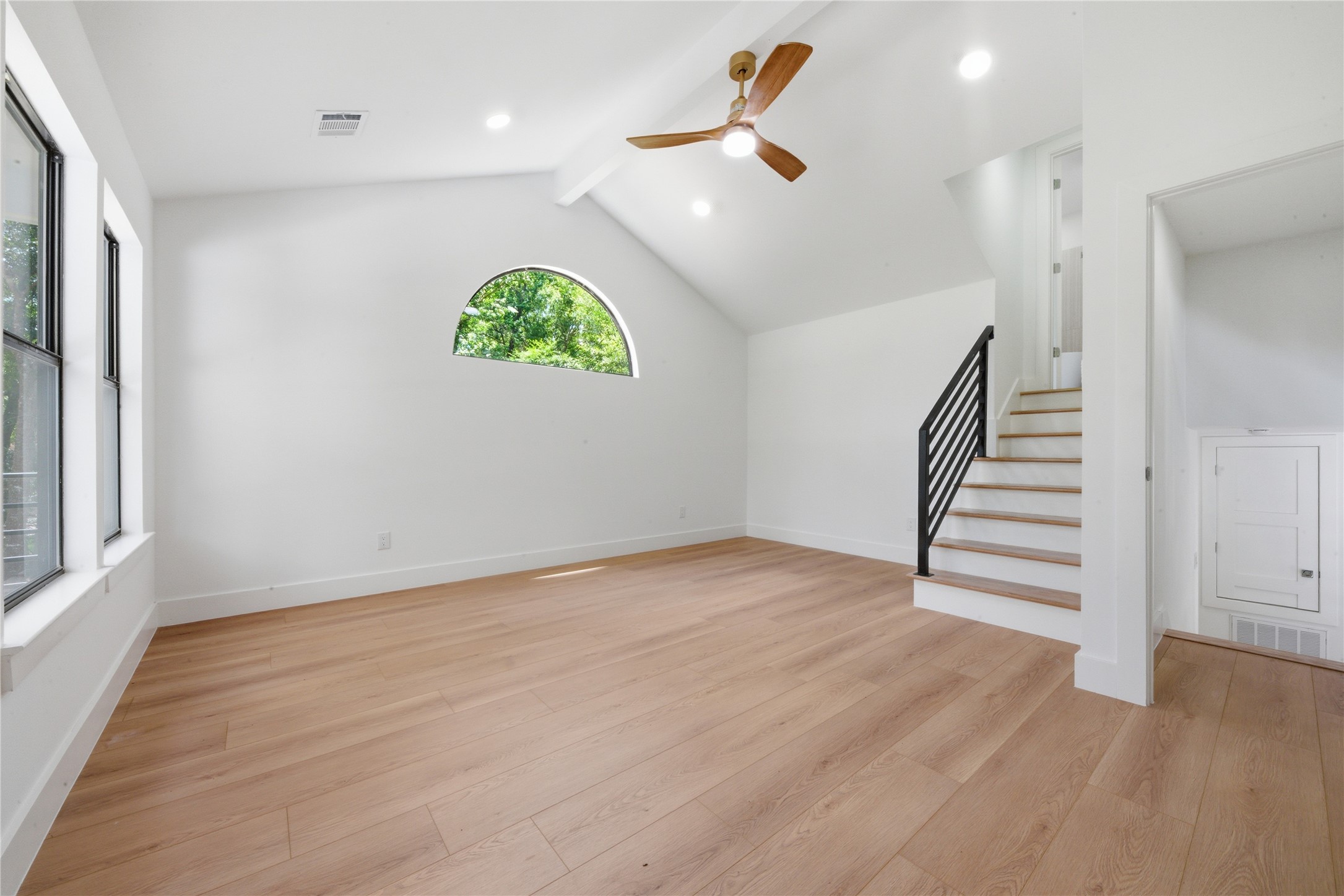 Stunning vaulted second primary suite featuring exposed white beam, half-moon accent window, and private interior staircase to the 4th-floor ensuite with soaking tub and walk-in closet.
