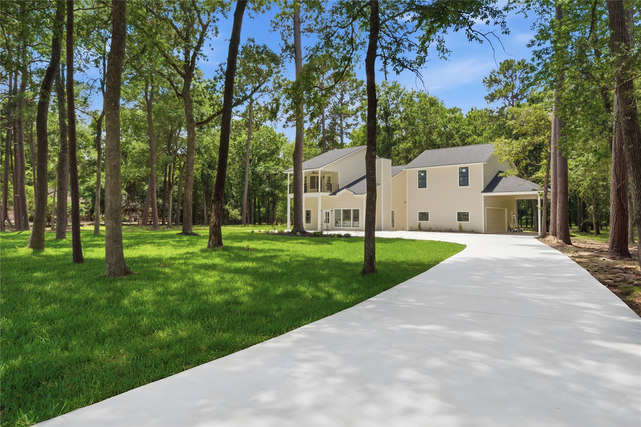 Long approach view of the property showing your home, covered drive-through, and detached structure positioned among mature pines. The 1.67-acre lot offers exceptional privacy from neighboring homes.