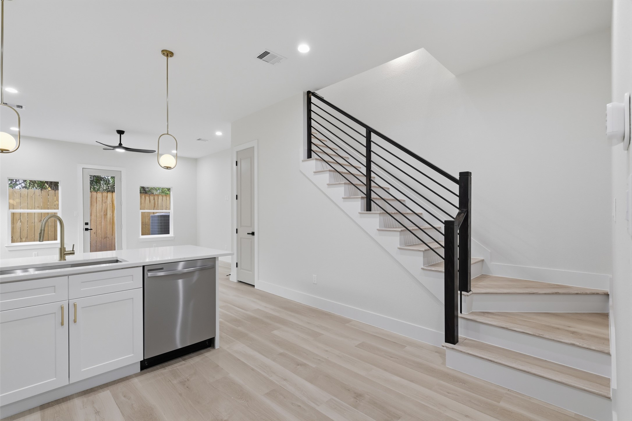 Bright and modern upstairs landing with sleek railings, recessed lighting, and access to a sunlit room, creating a welcoming and open atmosphere.
