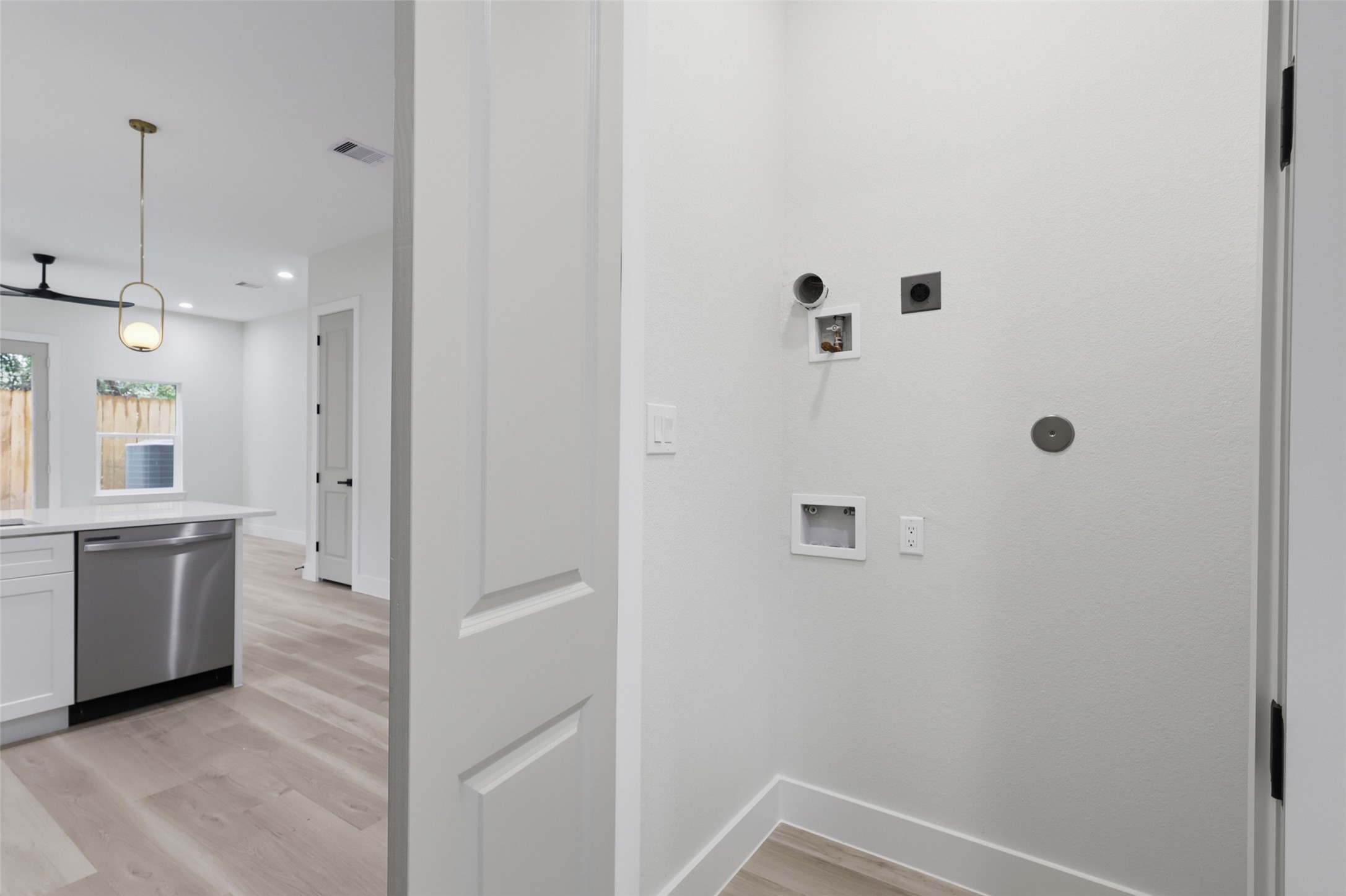 Bright and modern utility area with hookups for laundry, adjacent to an open-concept kitchen, located on the first floor, featuring sleek appliances and stylish lighting.