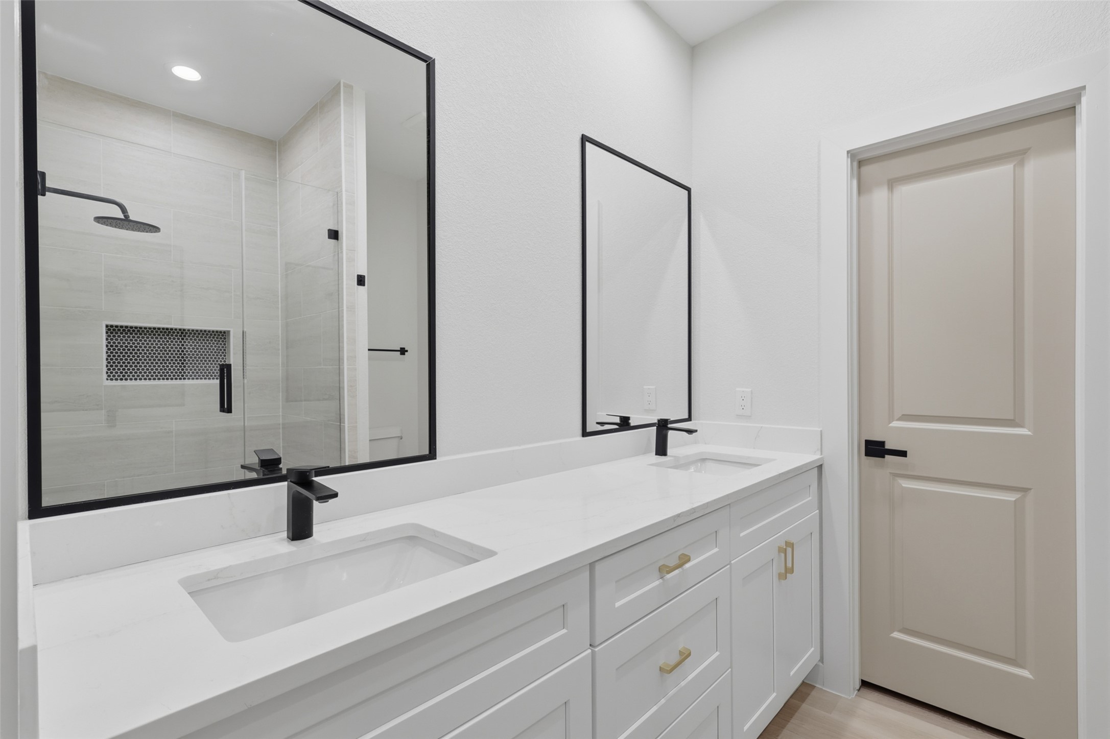 Elegant primary bathroom featuring a double vanity with sleek black fixtures and a spacious walk-in shower with modern tile design.