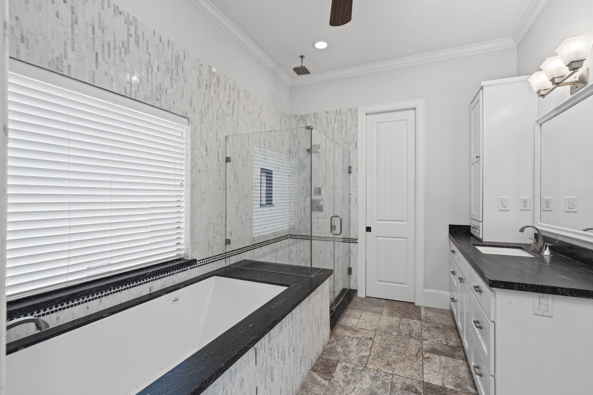 Primary Bathroom [9 x 16]  Third Floor. An intimate spa-inspired escape featuring a relaxing jetted soaking tub, separate glass-enclosed shower, and two individual vanity areas with shaker-style cabinetry. A thoughtful balance of everyday functionality and restorative comfort.