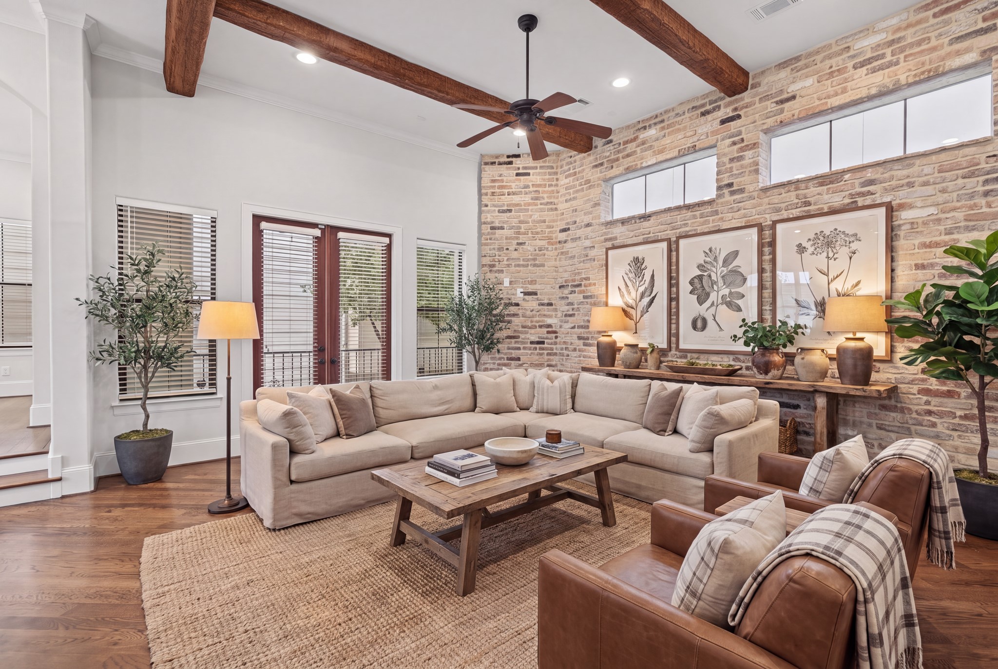Living Room [16 x 16]  Second Floor. Architectural character takes center stage with exposed wood ceiling beams, rich brick-clad accents, and beautiful natural light. An inviting setting for relaxed evenings or entertaining, where timeless textures lend warmth and distinction. Disclaimer: This room has been virtually staged.