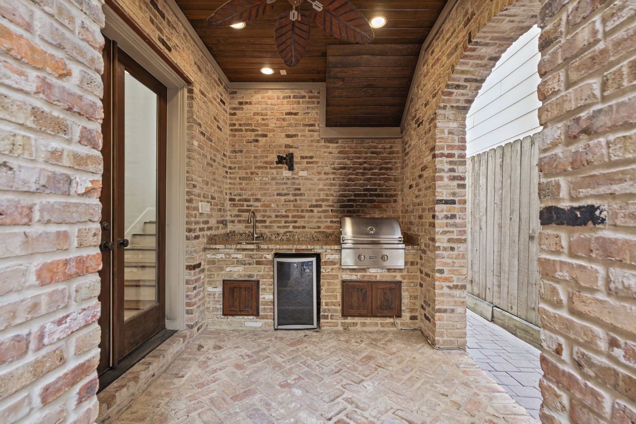 Summer Kitchen  Courtyard  Graceful brick arches frame this inviting outdoor culinary retreat, complete with a built-in Coyote grill, preparation sink, and beverage refrigerator. Just steps from the private plunge pool, it sets the scene for leisurely afternoons, alfresco dining, and memorable evenings with friends.