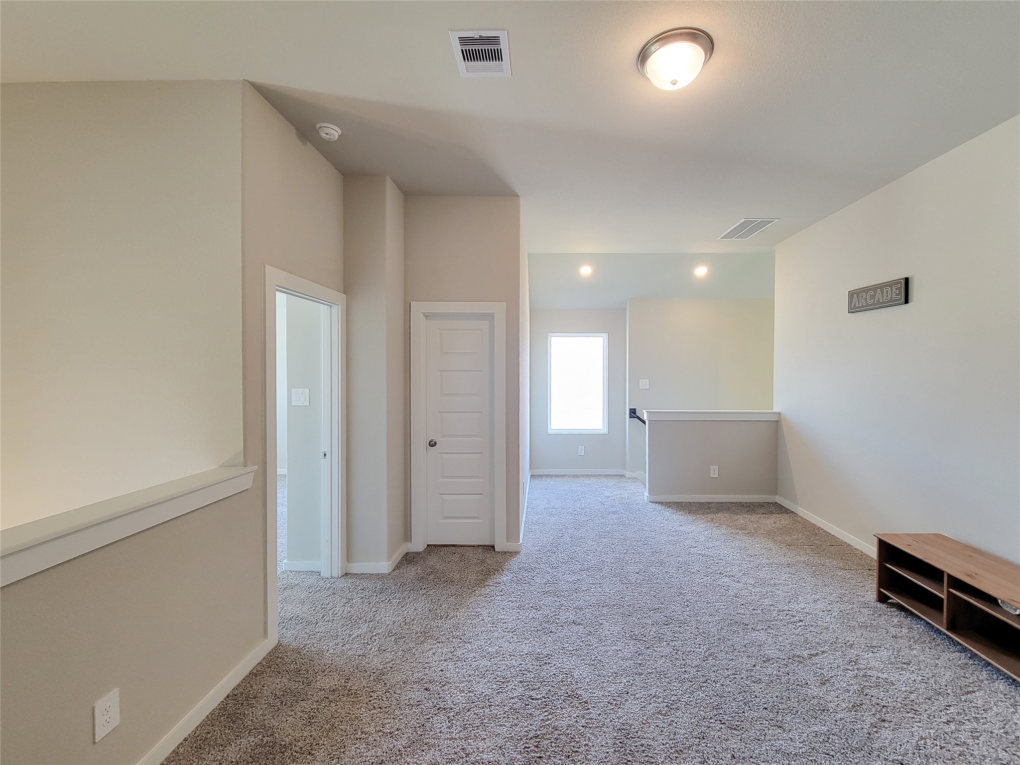 Spacious and well-lit carpeted area with neutral walls, ideal for a cozy family room or entertainment space.