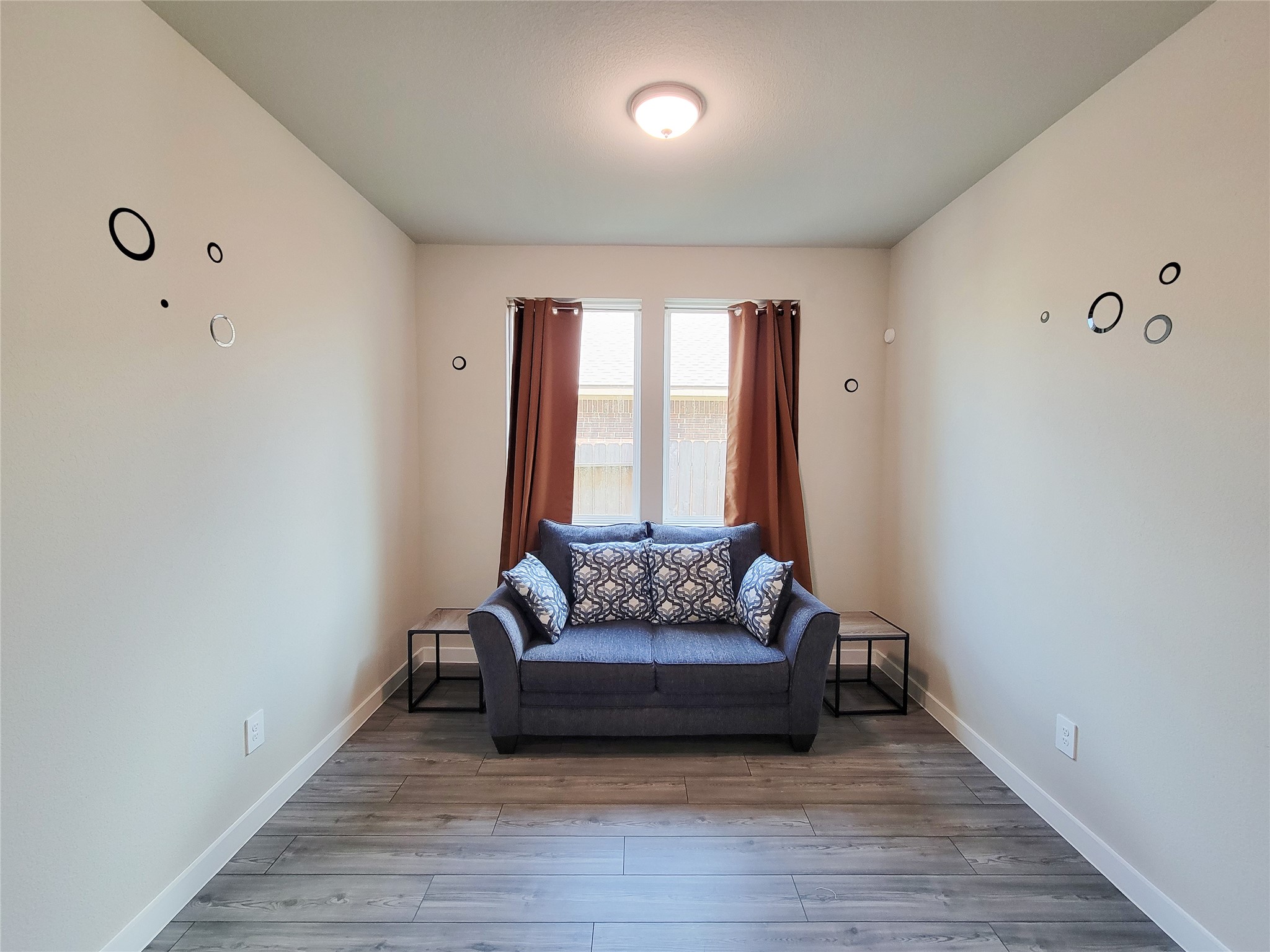 Cozy sitting area with modern decor, featuring a comfortable loveseat, accent pillows, and ample natural light from the window.