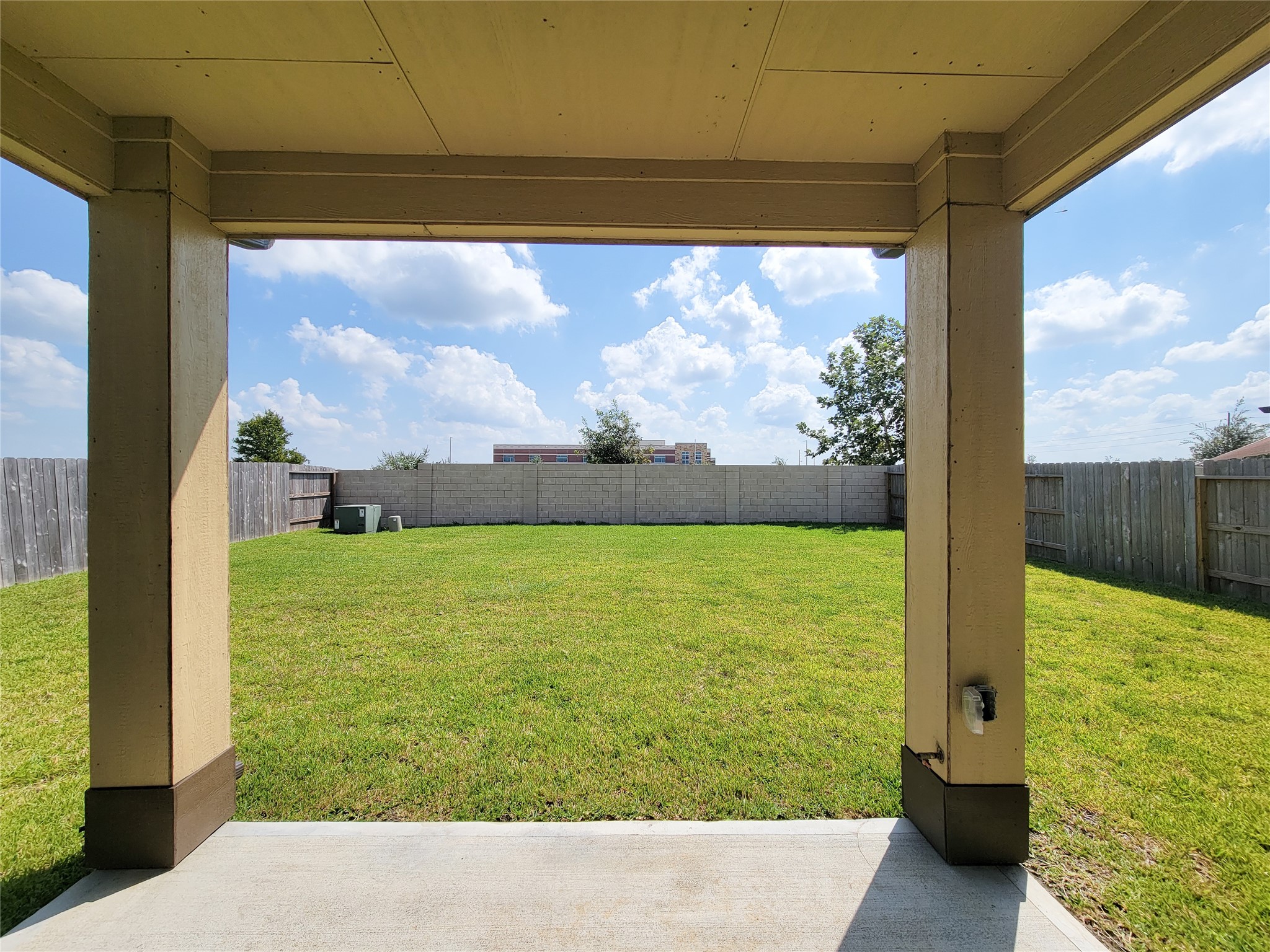 Expansive backyard with lush green lawn, perfect for outdoor activities and relaxation, framed by a covered patio offering a shaded retreat.