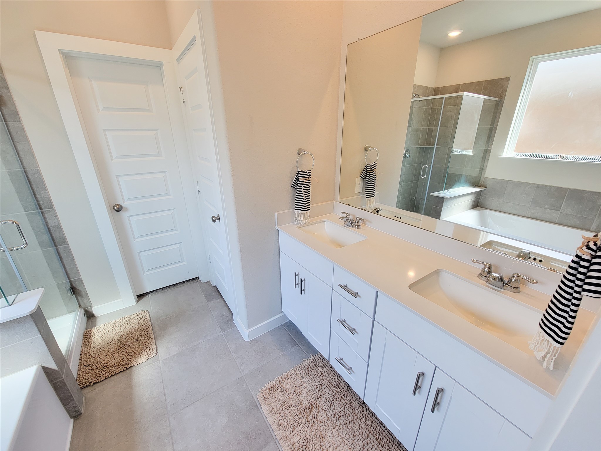 Elegant bathroom featuring a spacious double vanity with sleek fixtures, a large mirror, and a separate glass-enclosed shower.
