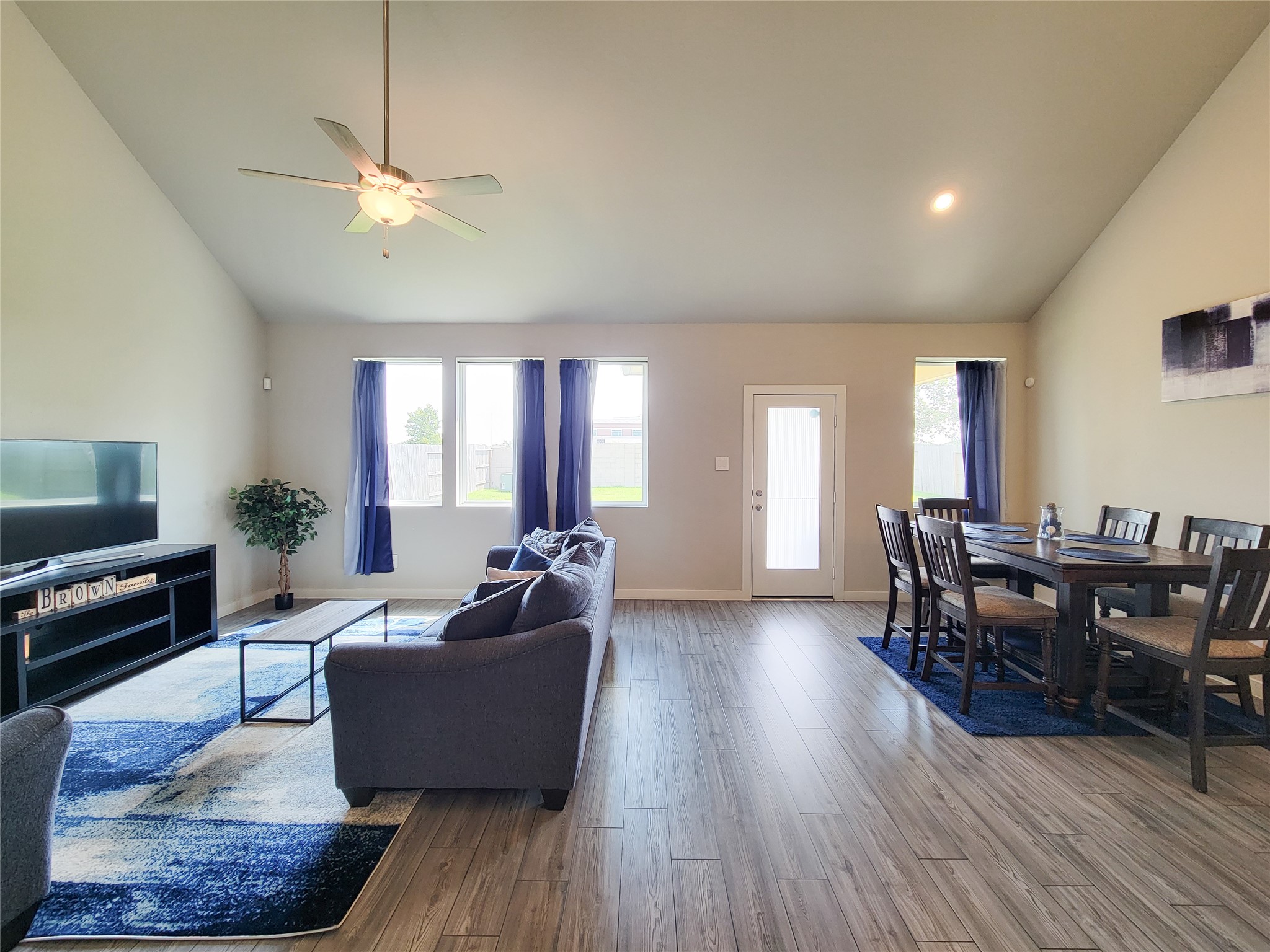 Spacious living and dining area with vaulted ceilings, abundant natural light, and elegant wood flooring, creating a warm and inviting atmosphere.