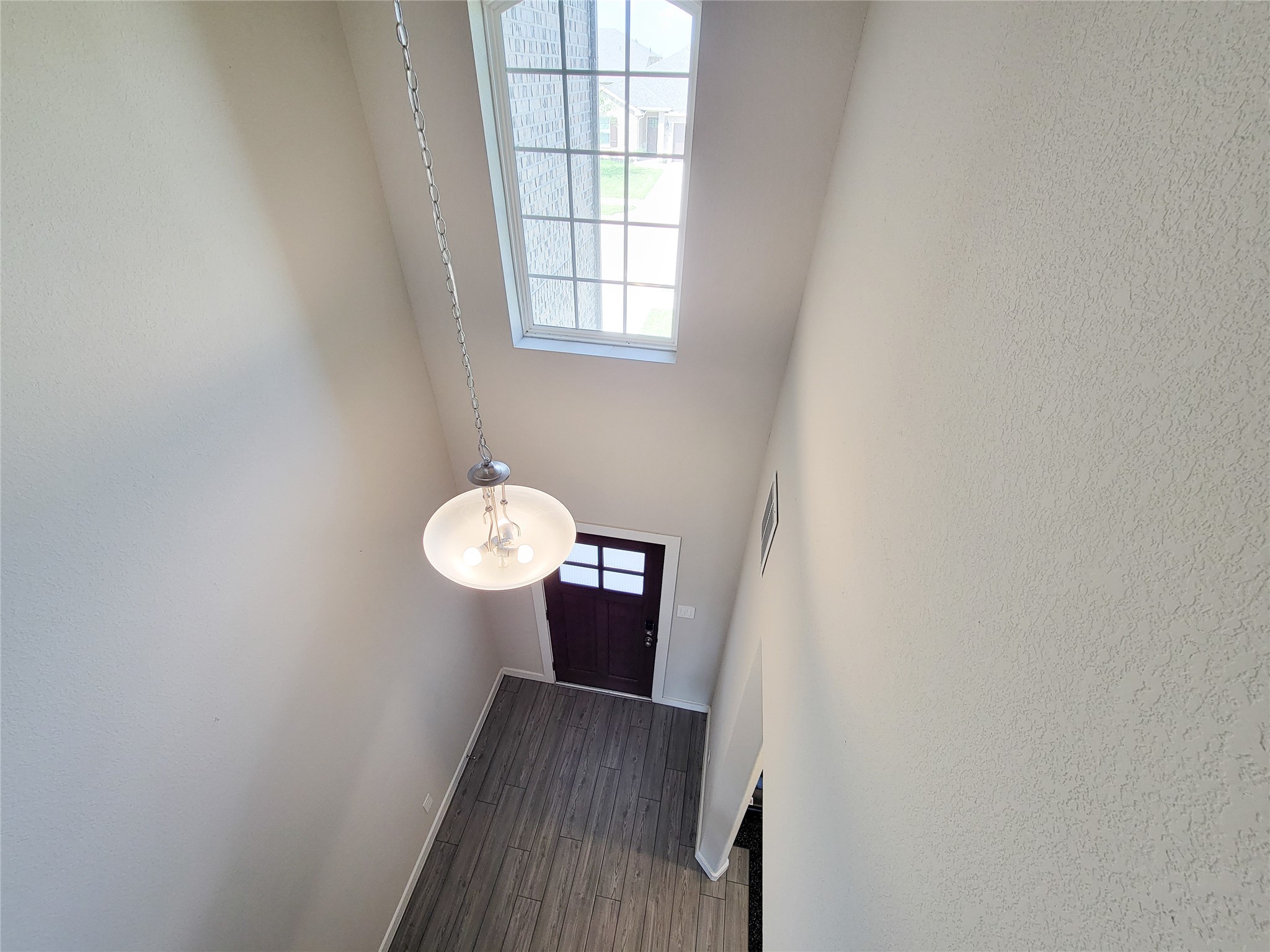 Bright and airy foyer with high ceilings, large window, and elegant hanging light fixture, welcoming you into the home.