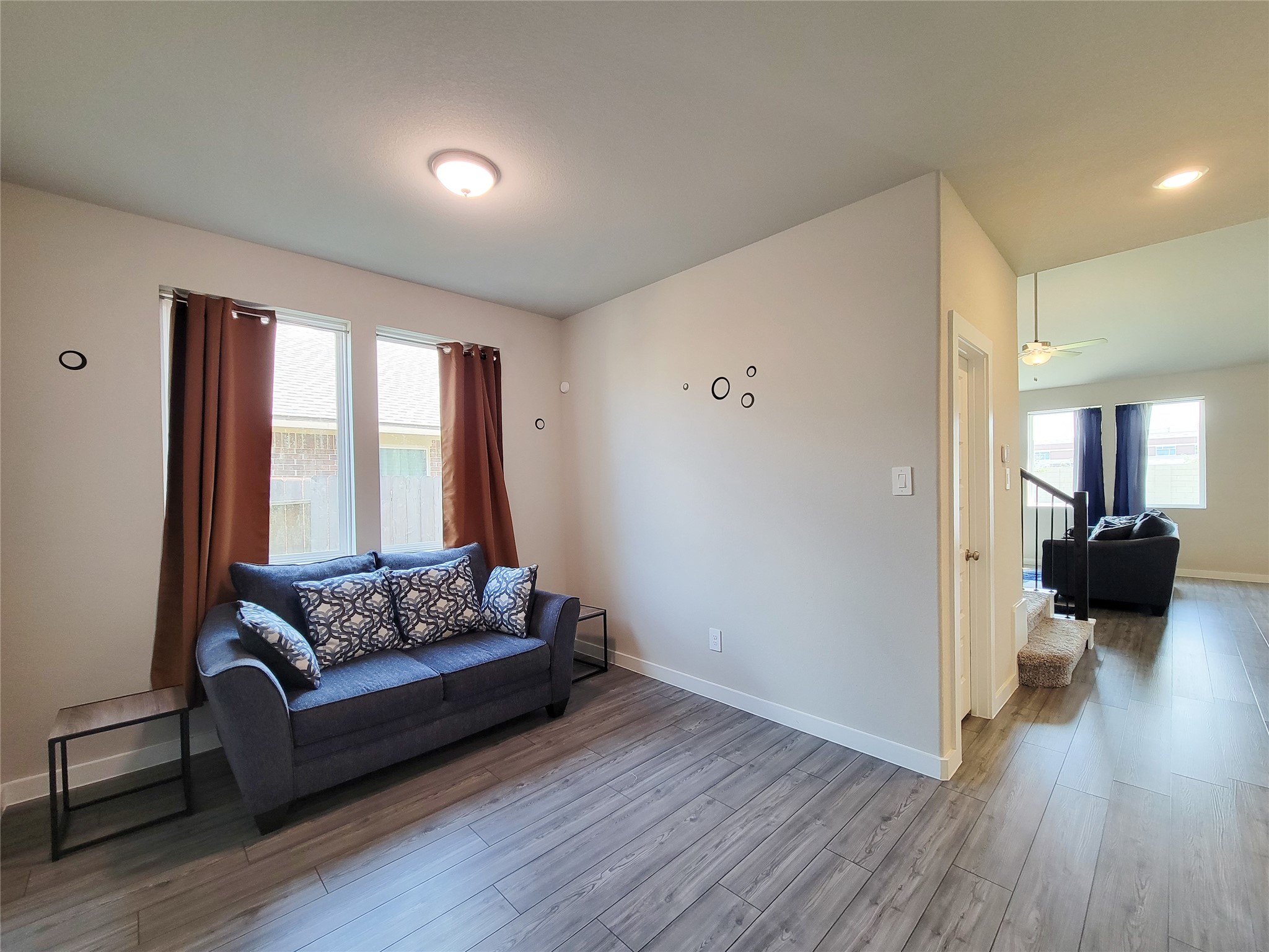 Bright and inviting living space featuring sleek hardwood floors, modern lighting, and ample natural light through large windows, perfect for relaxation and entertaining.