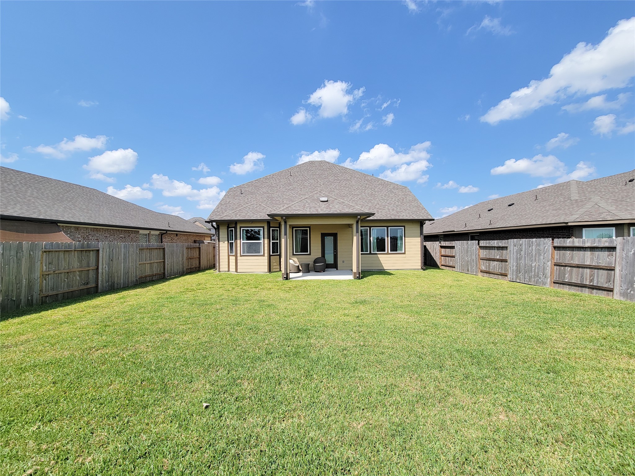 Spacious and inviting backyard with a well-maintained lawn, privacy fencing, and a charming covered patio perfect for outdoor gatherings.