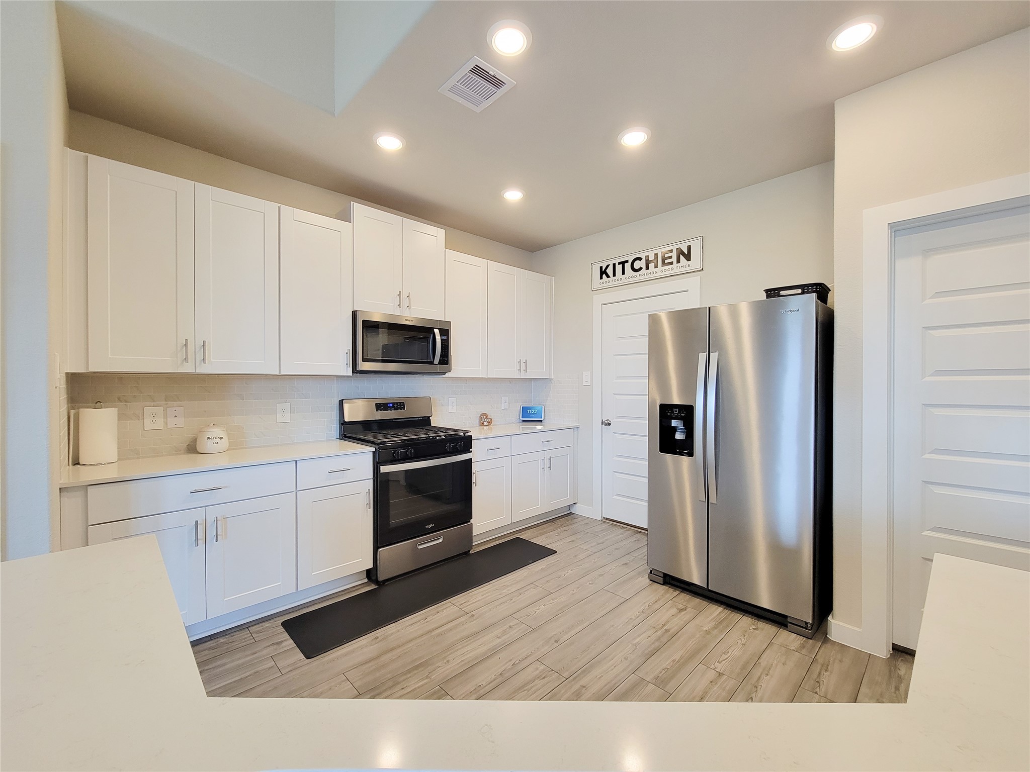 Modern kitchen with sleek stainless steel appliances, crisp white cabinetry, and stylish wood-look flooring, offering a bright and functional space for cooking and entertaining.