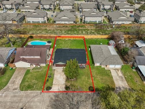 This aerial photo shows a single-story home with a newer roof, highlighted by a red boundary line. The property features a spacious front yard with a  two car driveway and a central tree.