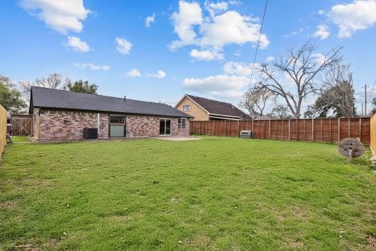 This photo shows a spacious backyard with a well-maintained lawn, bordered by a  new wooden fence. The house has a brick exterior and large windows, offering a cozy and private outdoor space ideal for family activities or entertaining.
