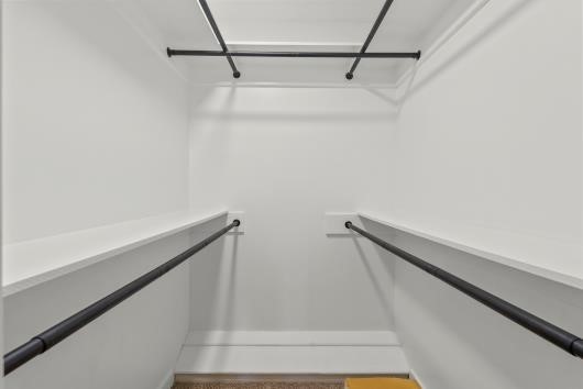 Spacious walk-in closet with multiple hanging rods, offering ample storage space and a clean, modern design. Primary bedroom