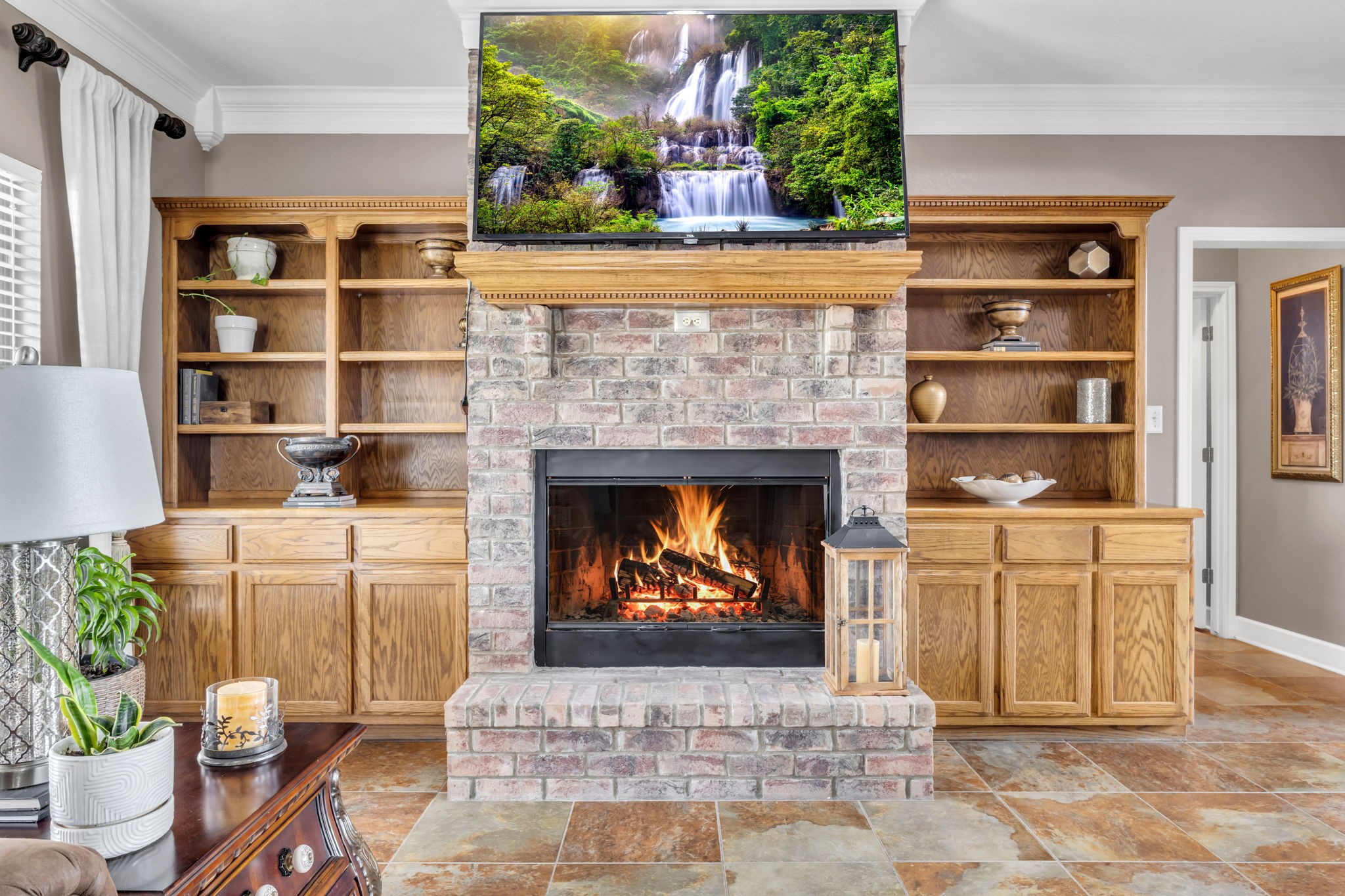 Beautiful brick fireplace serves as the focal point of the living room, complemented by wood built-ins with open shelving and lower cabinets for additional storage.
