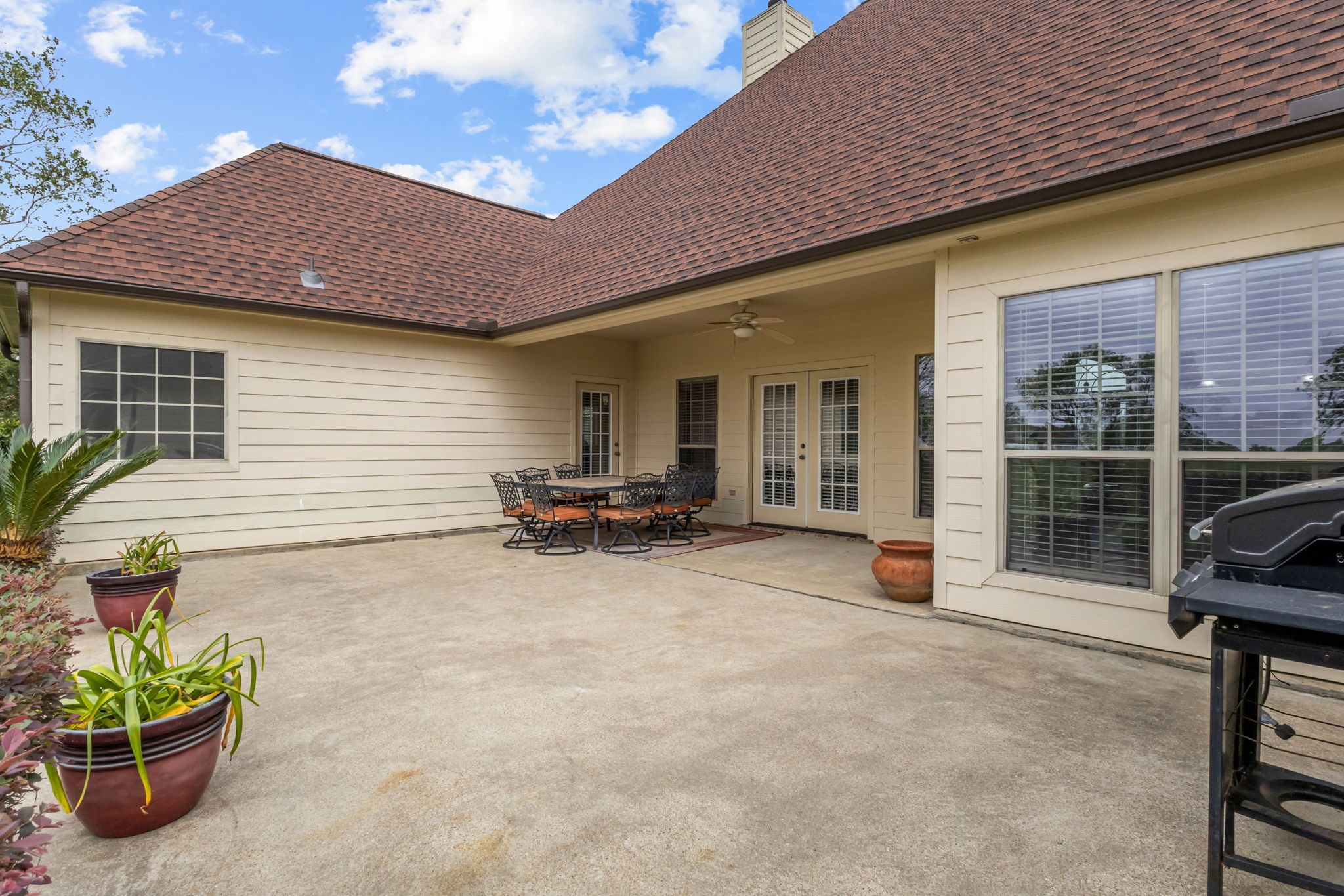 Extended back patio featuring both covered and open areas, offering plenty of space for outdoor entertaining, dining, and relaxation. French doors provide convenient access to the home, creating a welcoming space to enjoy outdoor living.