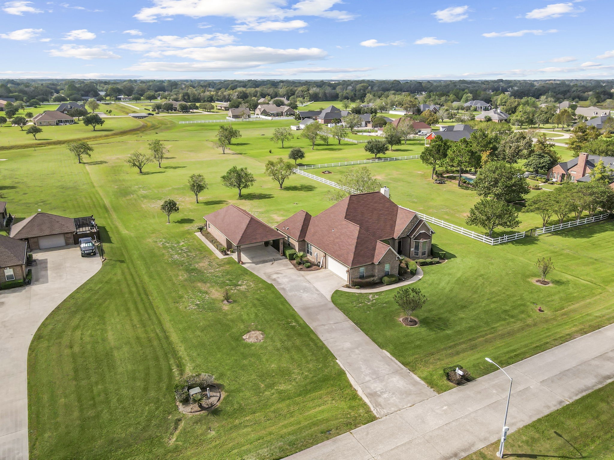 Another stunning aerial view highlighting the property's expansive 2+ acres, attractive brick exterior, and detached garage with covered parking. Surrounded by open green space and mature trees, this property offers room to spread out while enjoying the beauty of its spacious surroundings.