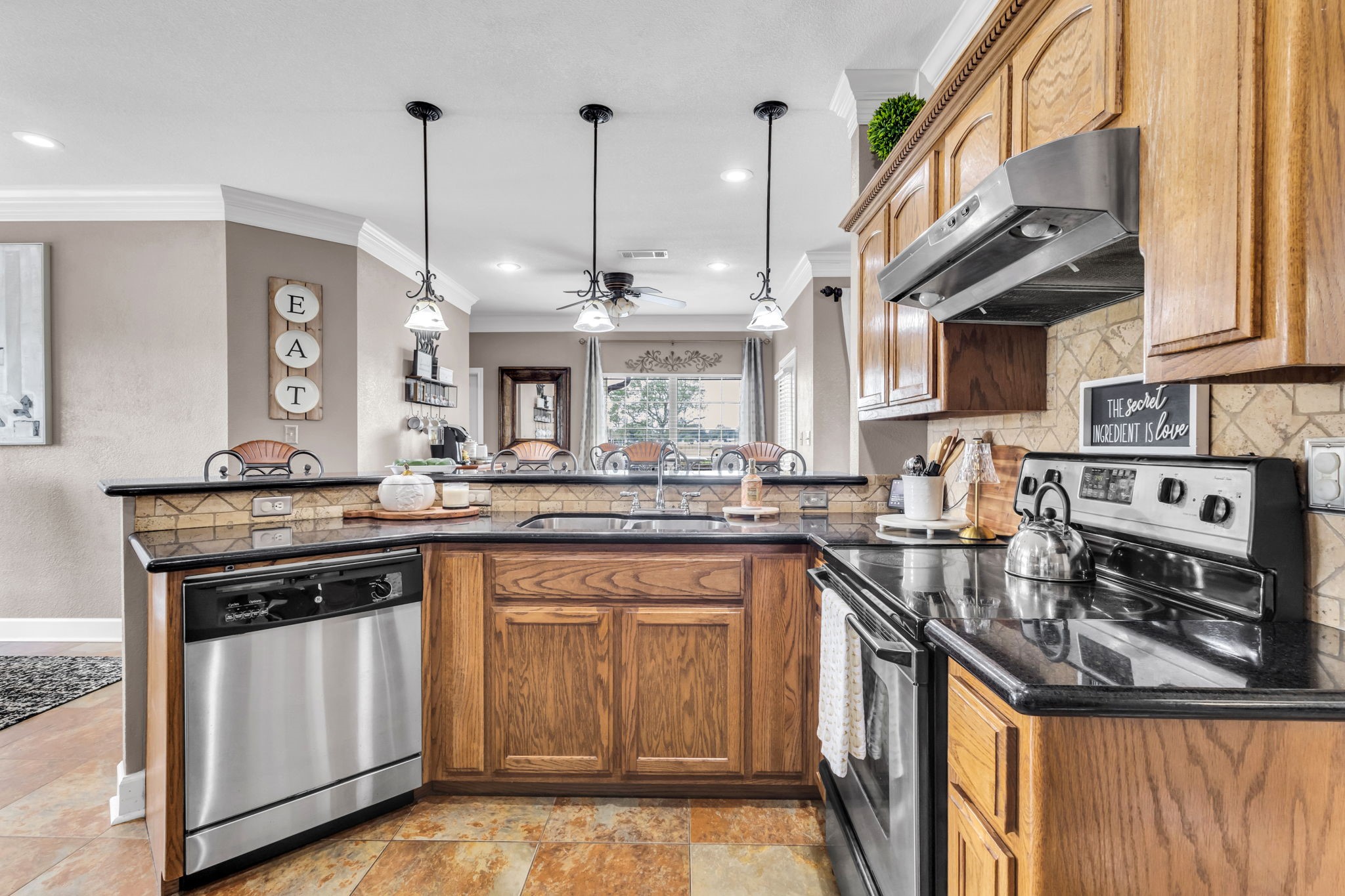Kitchen offers plenty of cabinet and counter space, a double sink, and a decorative tile backsplash. The open breakfast bar connects to the dining area, making the space convenient for everyday living and entertaining.