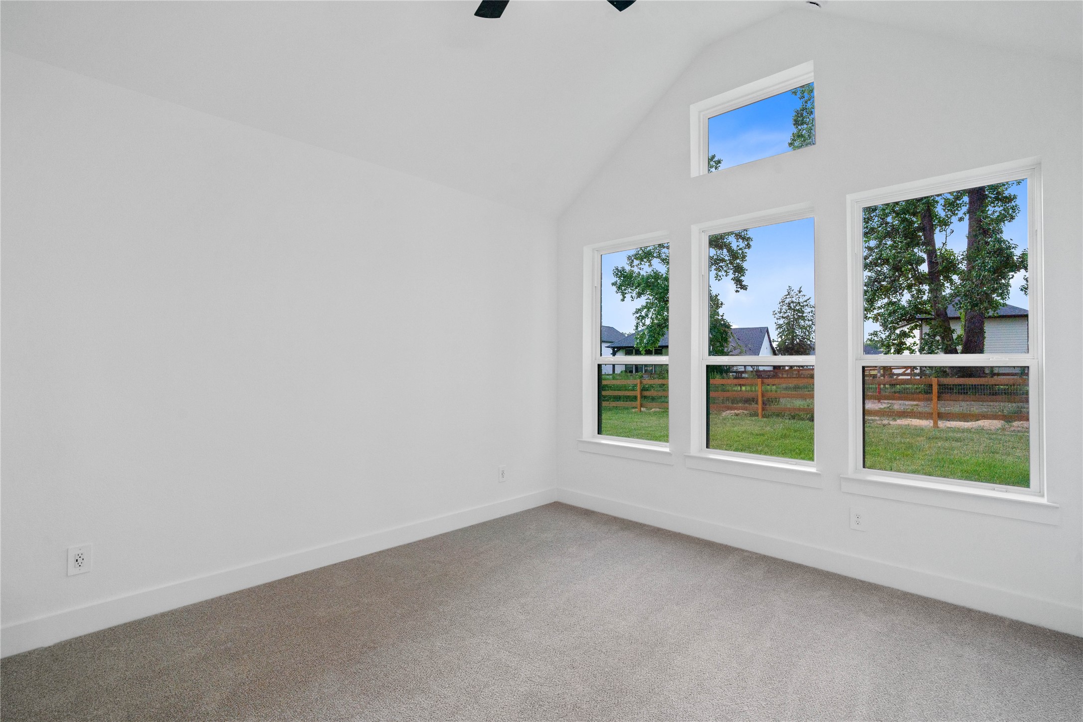 Relax and unwind after a long day in this impressive primary suite! This generously sized room offers wood tile flooring, neutral-toned paint, high sloped ceilings with a ceiling fan, and large windows for added comfort and tranquility.