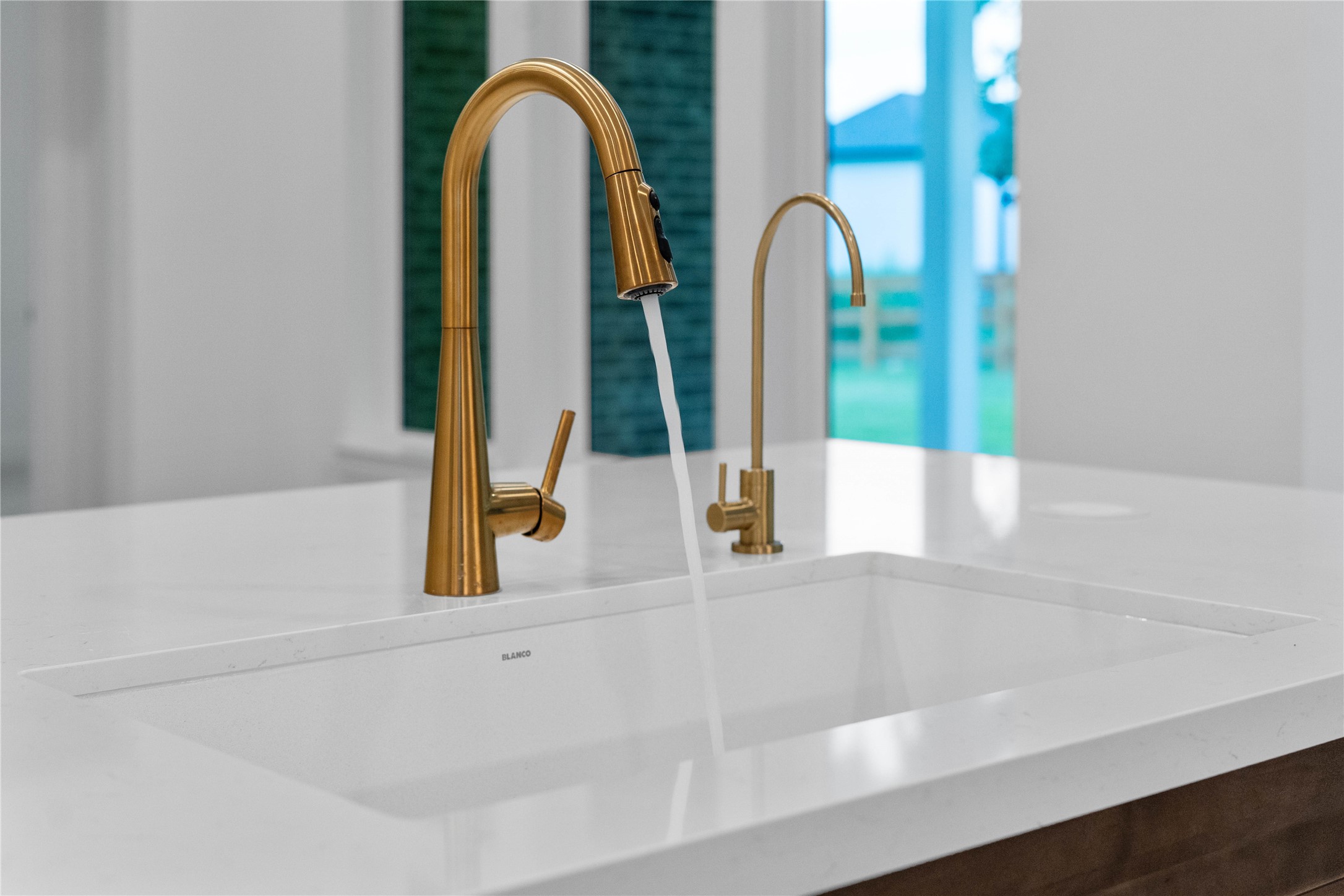 A high-end, under-mount single-basin sink is paired with dual champagne bronze fixtures, perfectly blending gourmet utility with a luxury aesthetic.