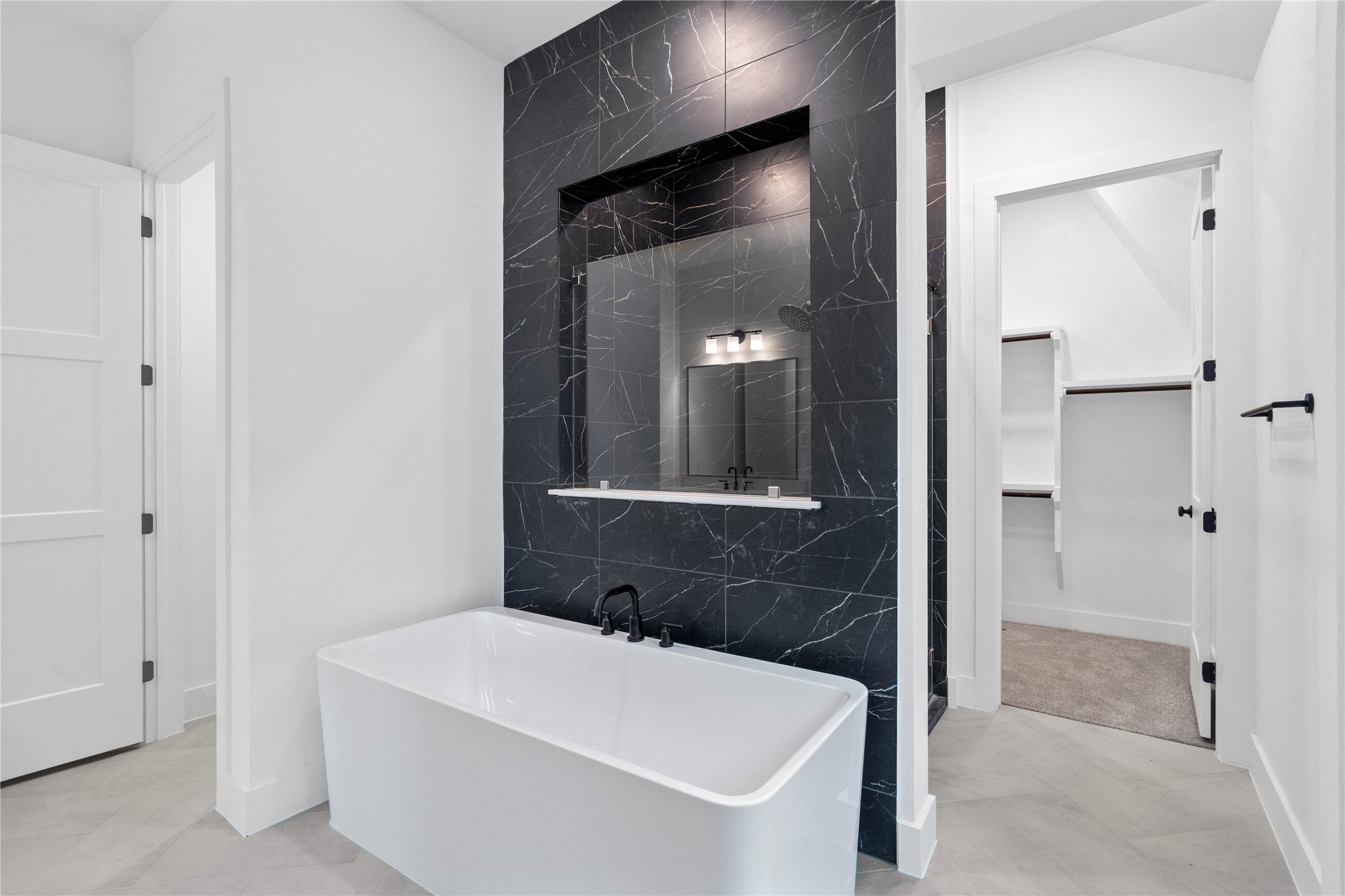 This alternate view of the primary bathroom showcases a large soaking tub perfect for unwinding after a long day, walk-in shower with a stylish tile surround, and a large walk-in closet!