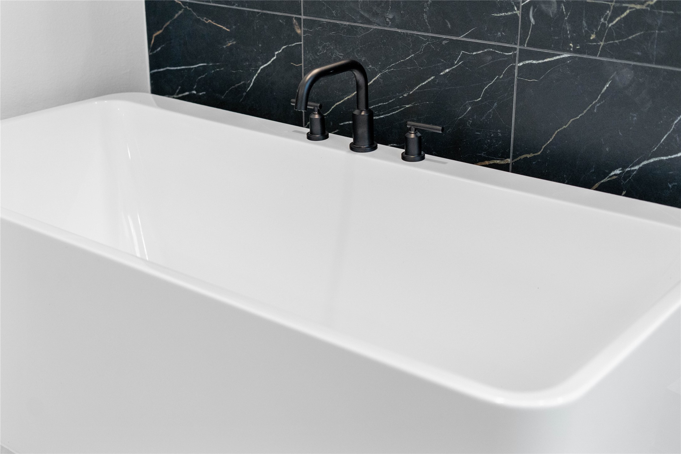 Indulge in the primary bath's deep, built-in soaking tub with elegant matte black fixtures and a sleek black tile surround for a true spa-like retreat.