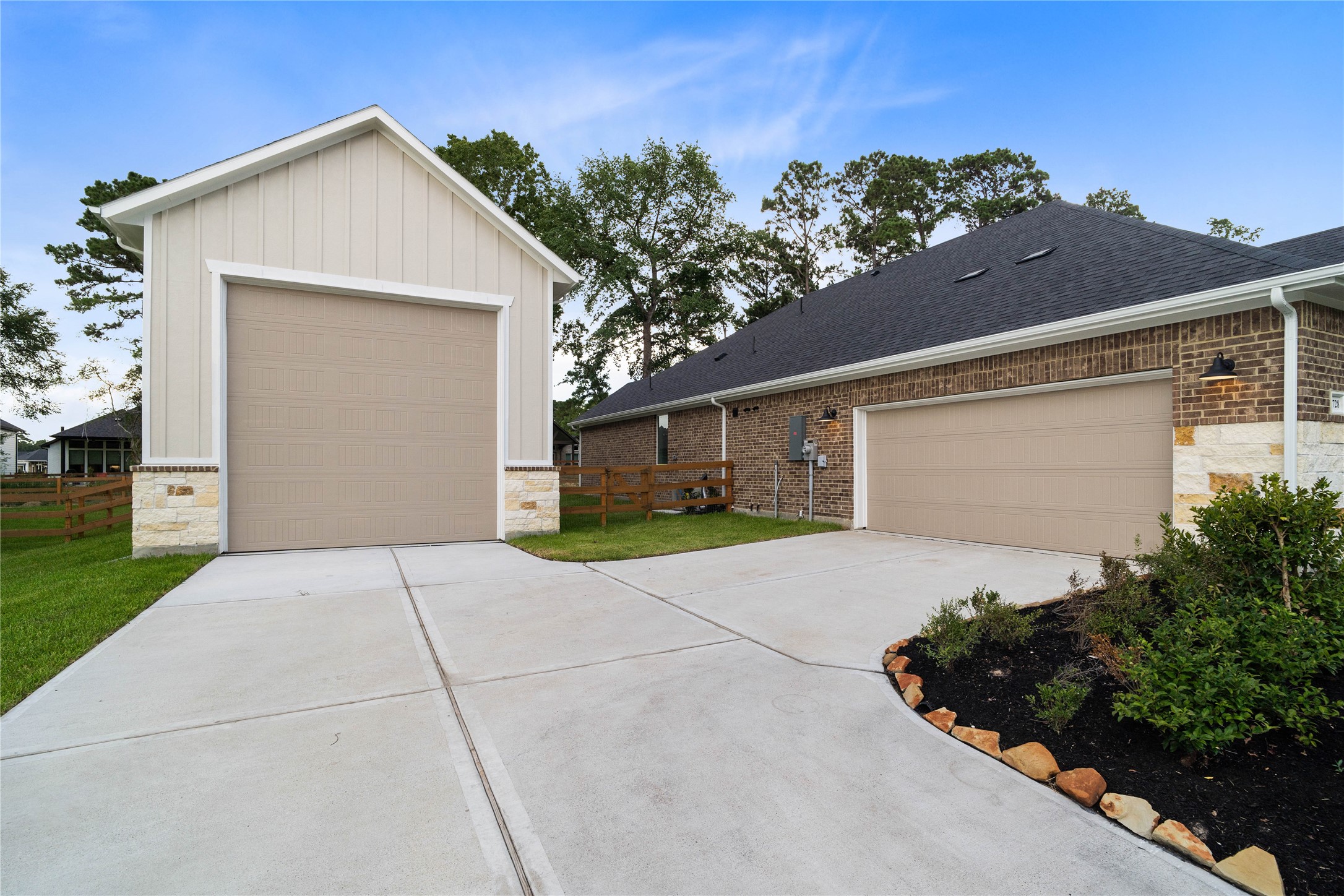 An expansive concrete driveway connects a detached, high-clearance RV garage with an attached two-car garage, providing a massive parking footprint with plenty of space for multiple vehicles, watercraft, and toys.