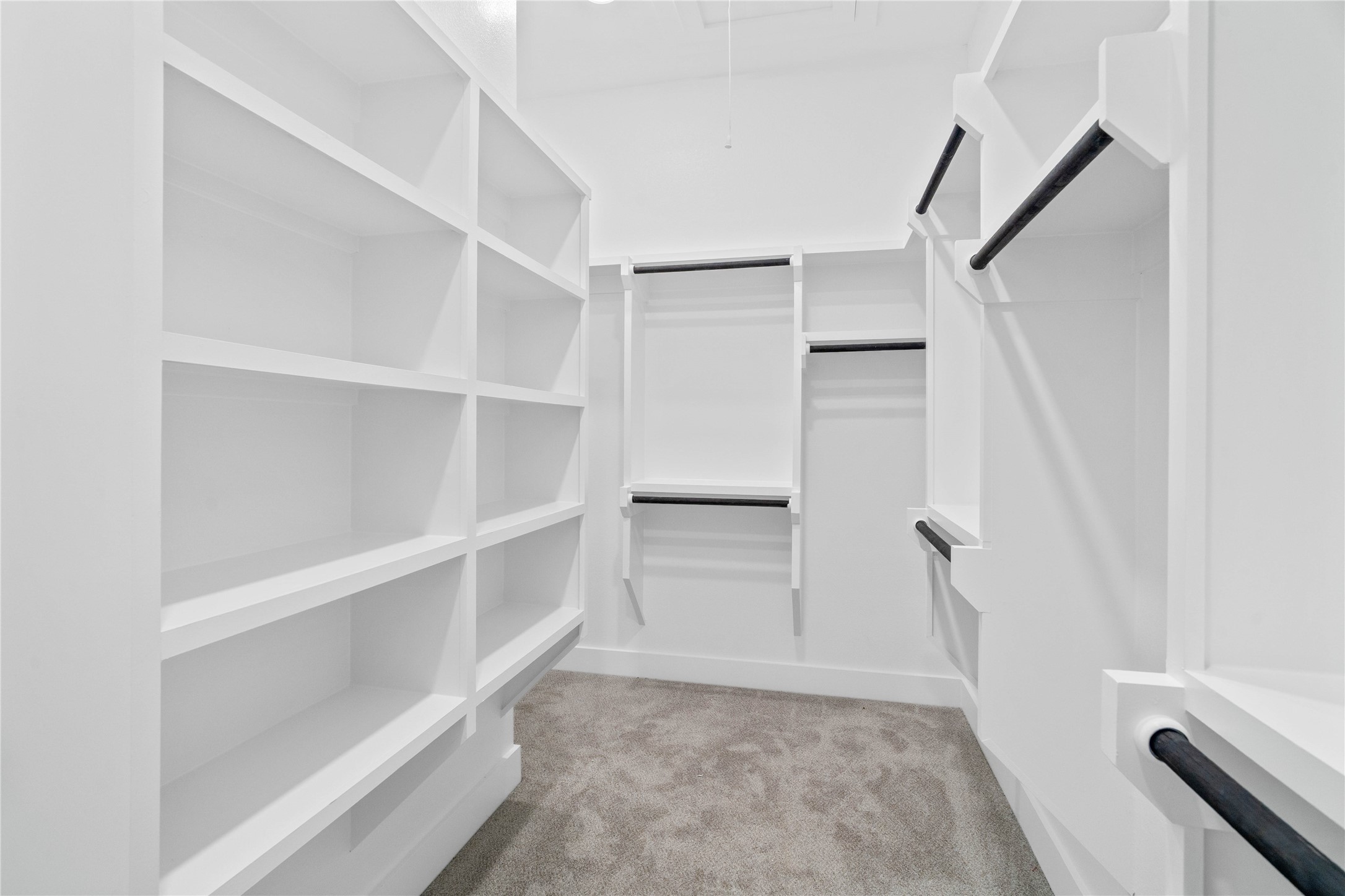 An expansive walk-in primary closet features extensive custom-built storage systems designed to maximize organization and wardrobe storage.