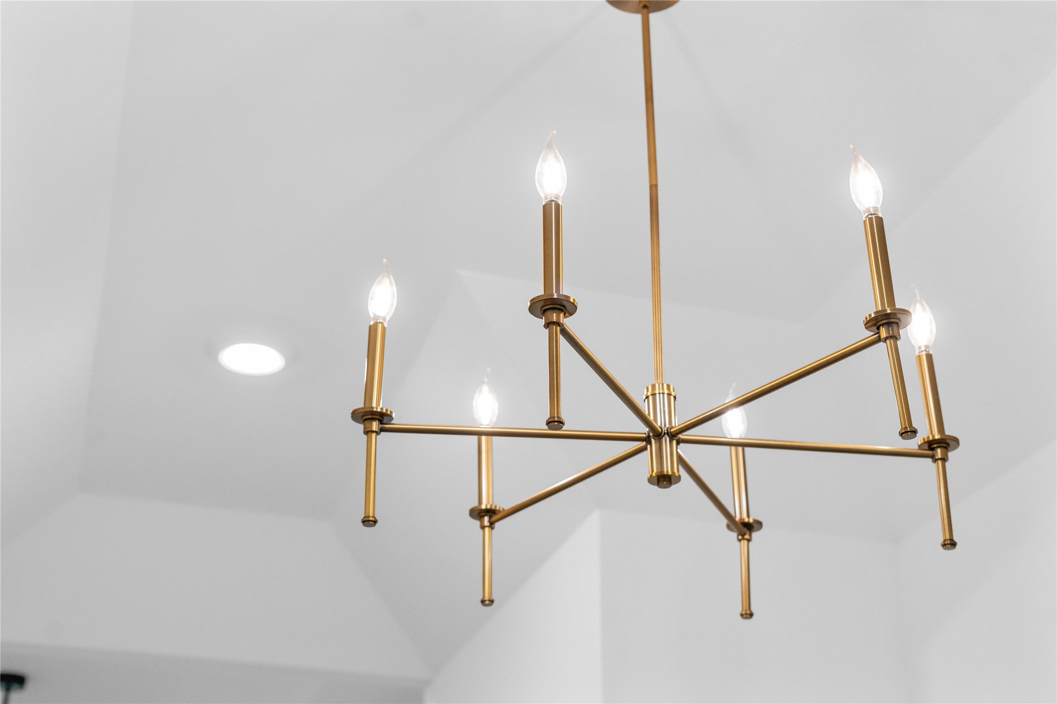 A striking modern brass chandelier acts as a sophisticated focal point in the entryway, casting a warm, elegant glow that immediately elevates the home's interior design.
