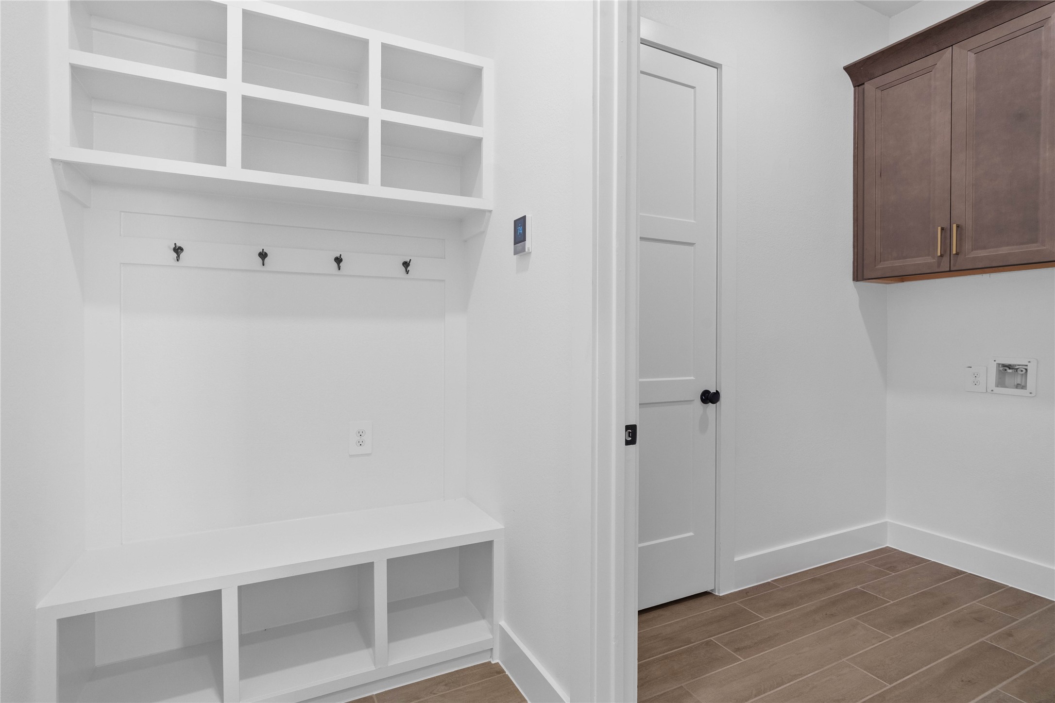 A custom-built mudroom drop zone stands adjacent to a spacious laundry room, offering the ultimate combination of home organization and everyday functionality.