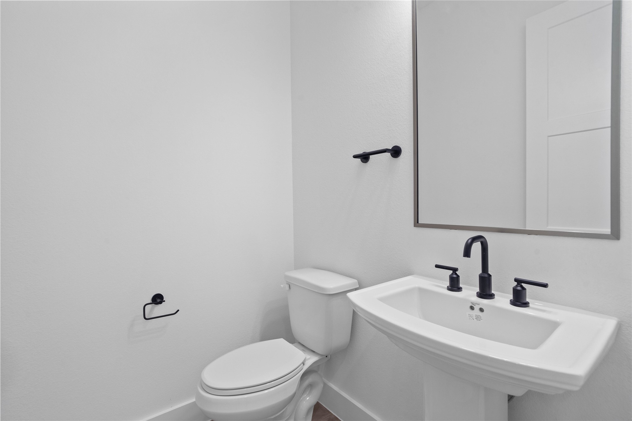 This crisp and contemporary powder room offers a sleek, minimalist design that provides a functional yet high-end experience for guests.