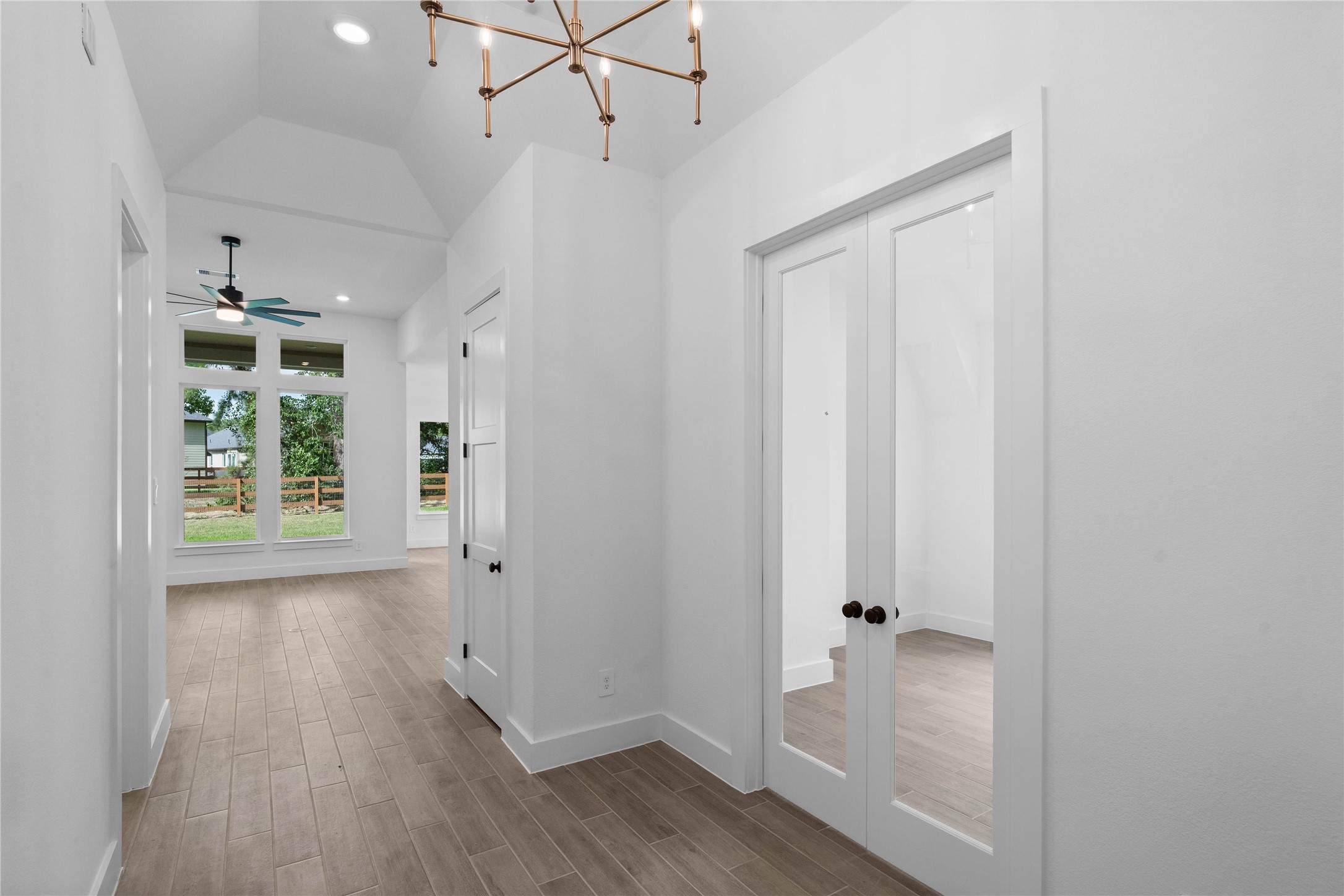 This elegant main hallway transitions beautifully into a dedicated home office, highlighted by sophisticated glass French doors that blend privacy with an open, airy feel.
