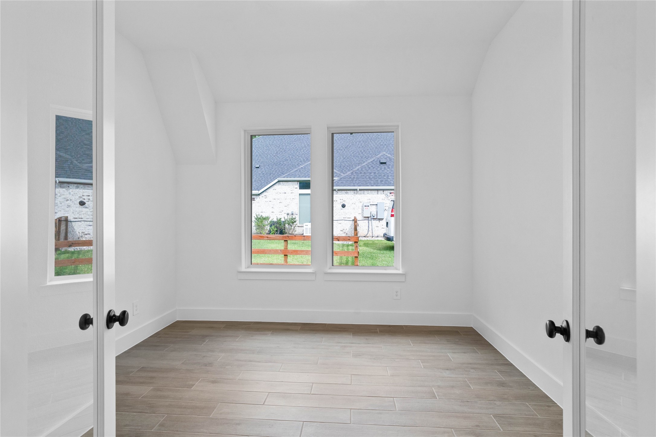 Framed by elegant French doors, this bright study offers a quiet, sophisticated space to work from home, defined by a distinct sloped ceiling that adds architectural character.