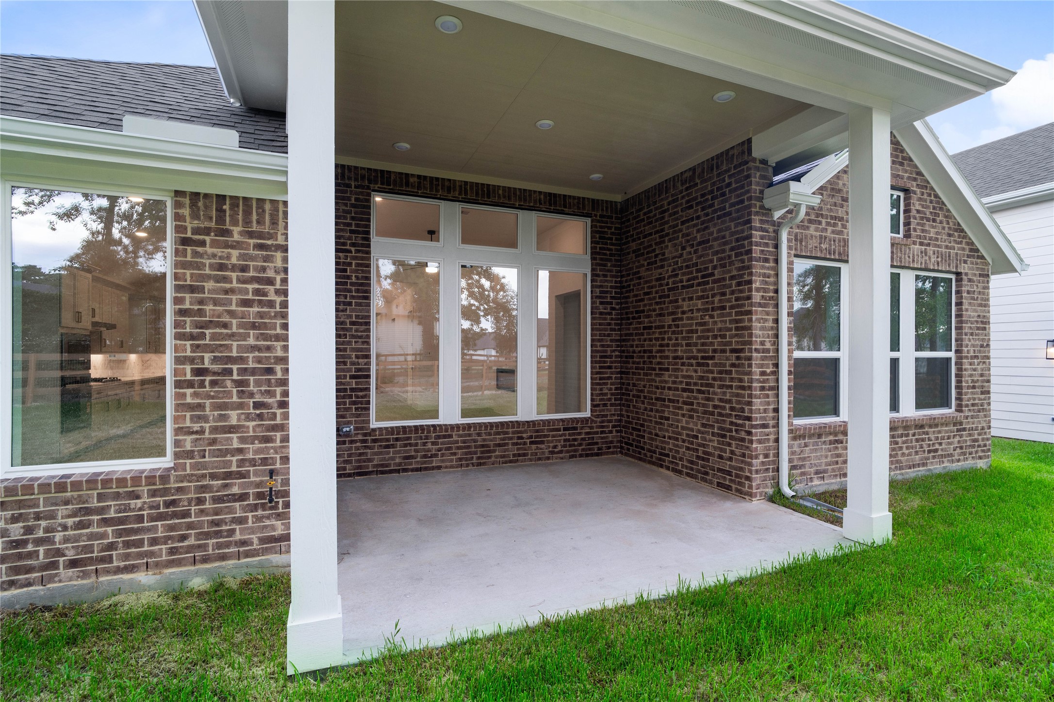 A deeply recessed covered back patio serves as a sheltered outdoor retreat, providing a seamless transition between the main home and the backyard.