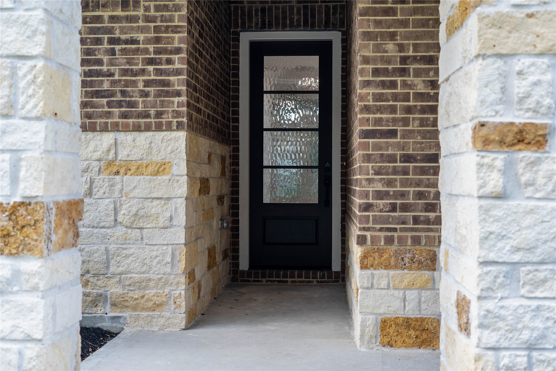 This entryway blends traditional masonry textures with modern door design to create a welcoming, upscale facade  that delivers instant curb appeal.