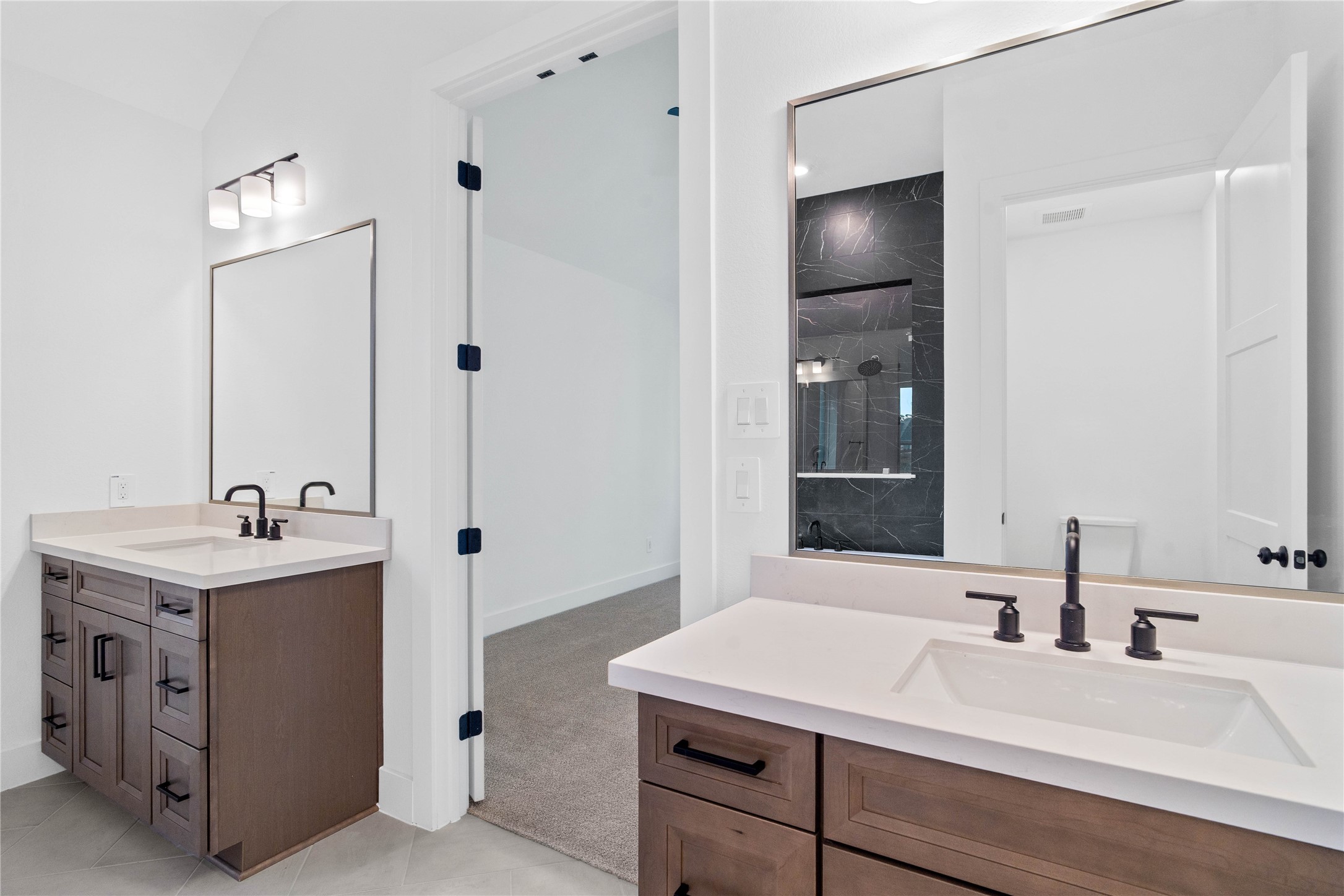 This stunningly updated primary bathroom is truly move-in ready! It features gorgeous painted dual vanity cabinetry with light countertops, large framed mirrors, soaring ceilings, custom paint, and sleek modern fixtures.