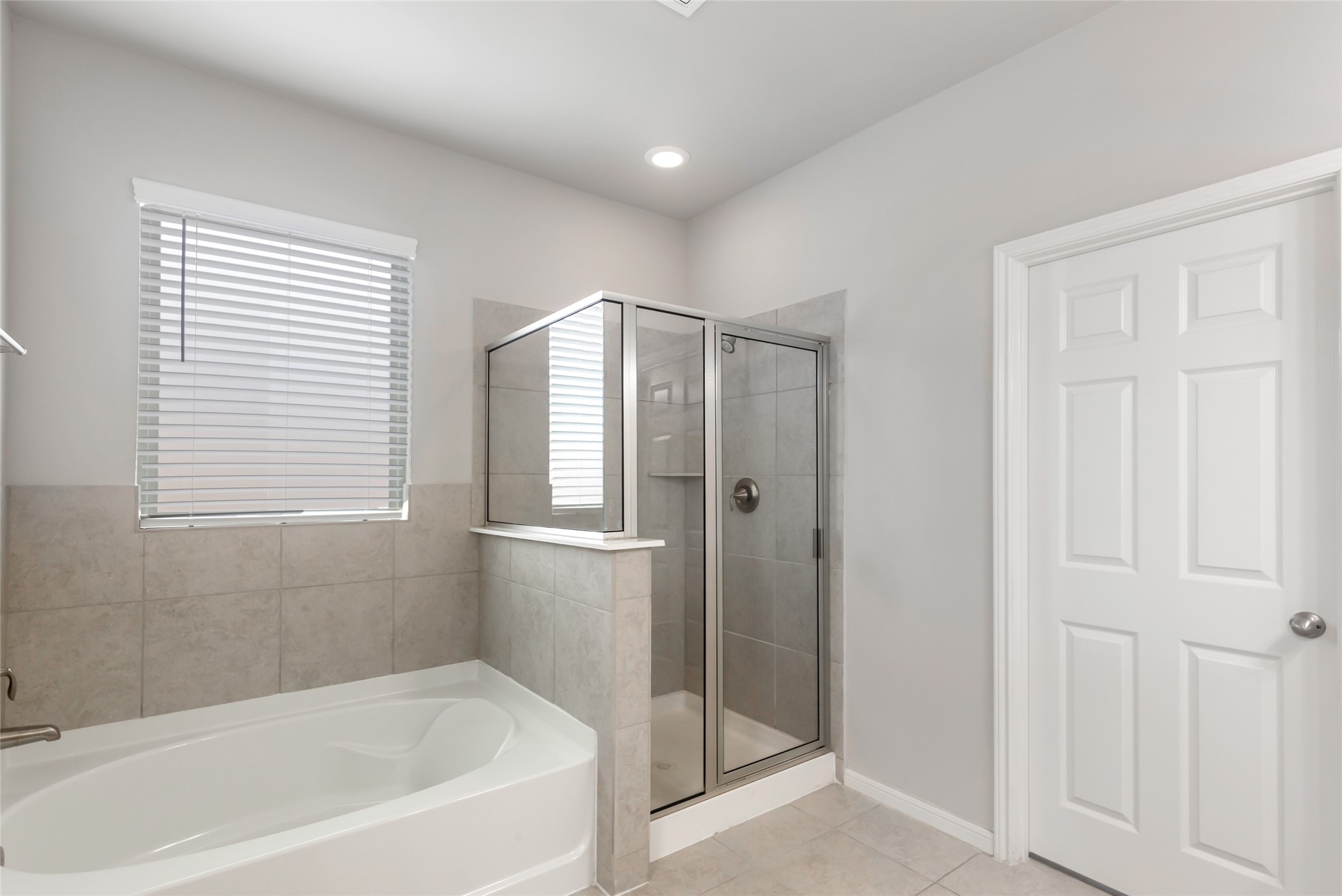 Bright primary bathroom offers a relaxing soaking tub, separate glass-enclosed shower and dual-sink vanity.