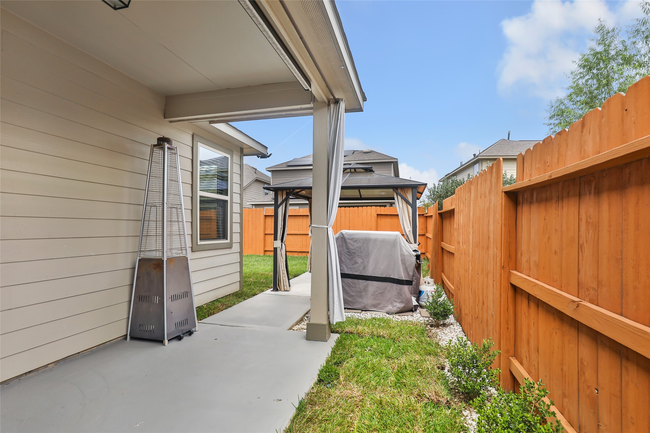 Spacious fenced backyard features a covered patio and additional outdoor living space.