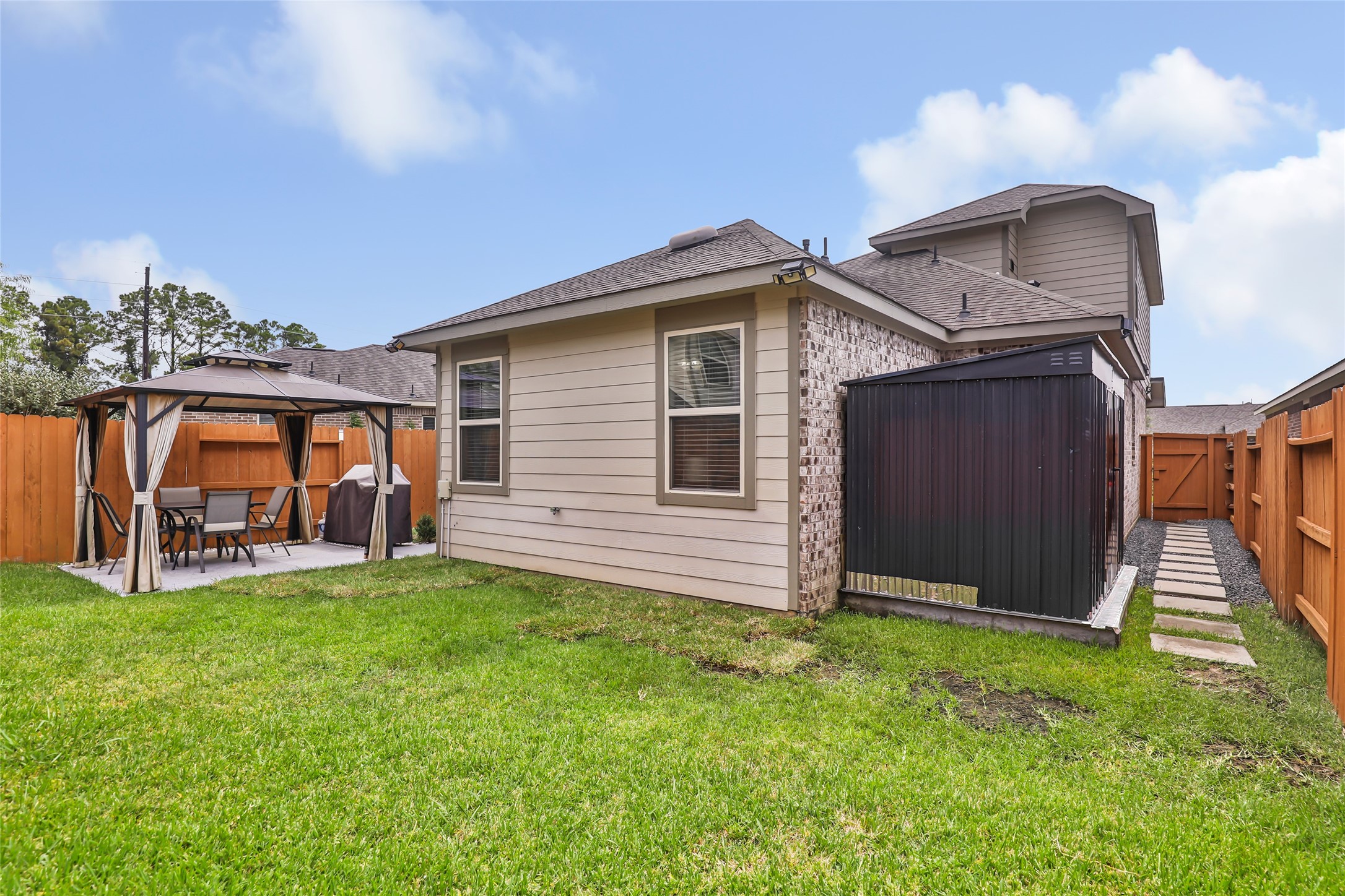 View of the fenced backyard, custom shed, and side-yard access, showcasing the home's outdoor space and privacy.