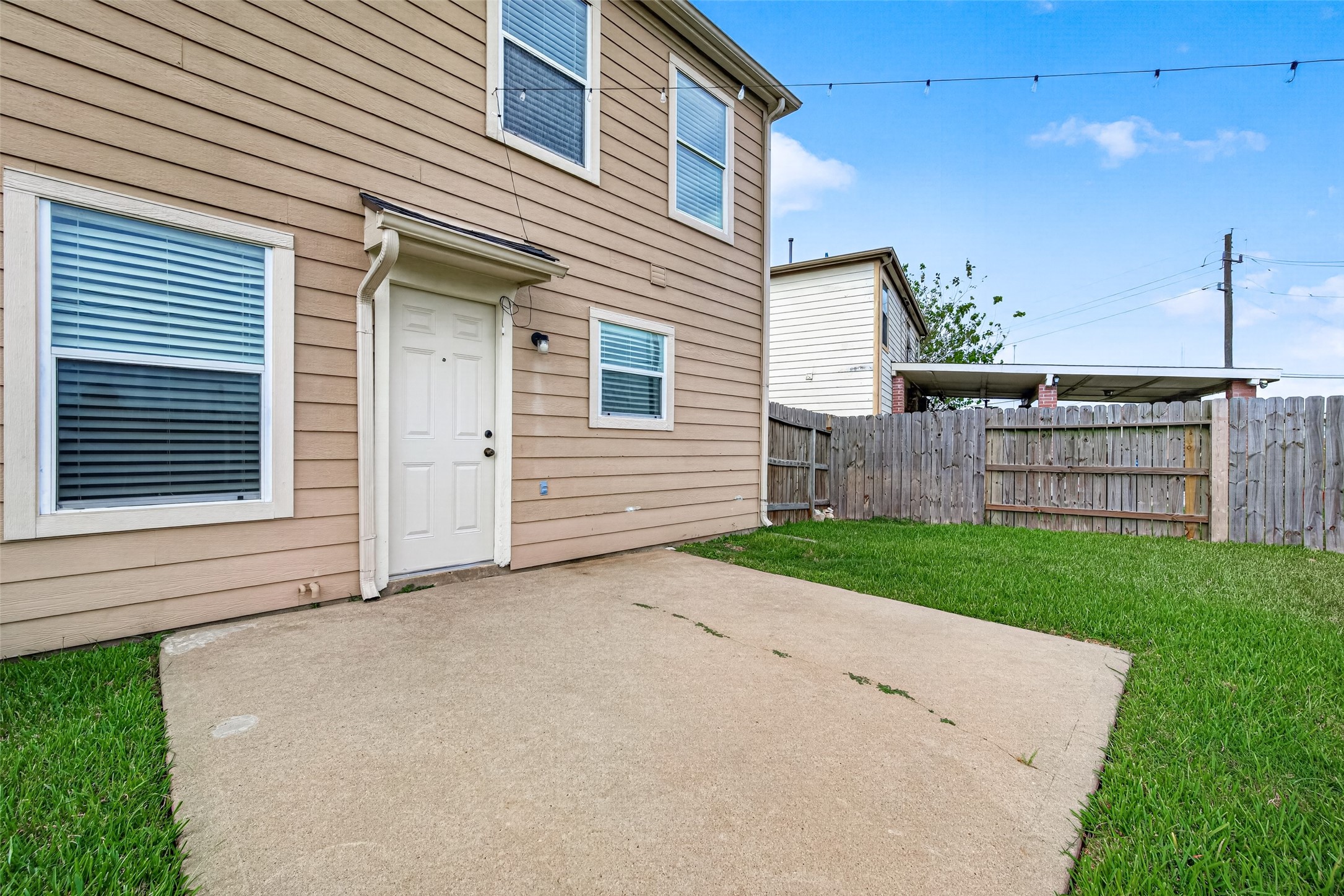 This fully fenced backyard features a spacious concrete patio flooring perfect for outdoor furniture and entertaining