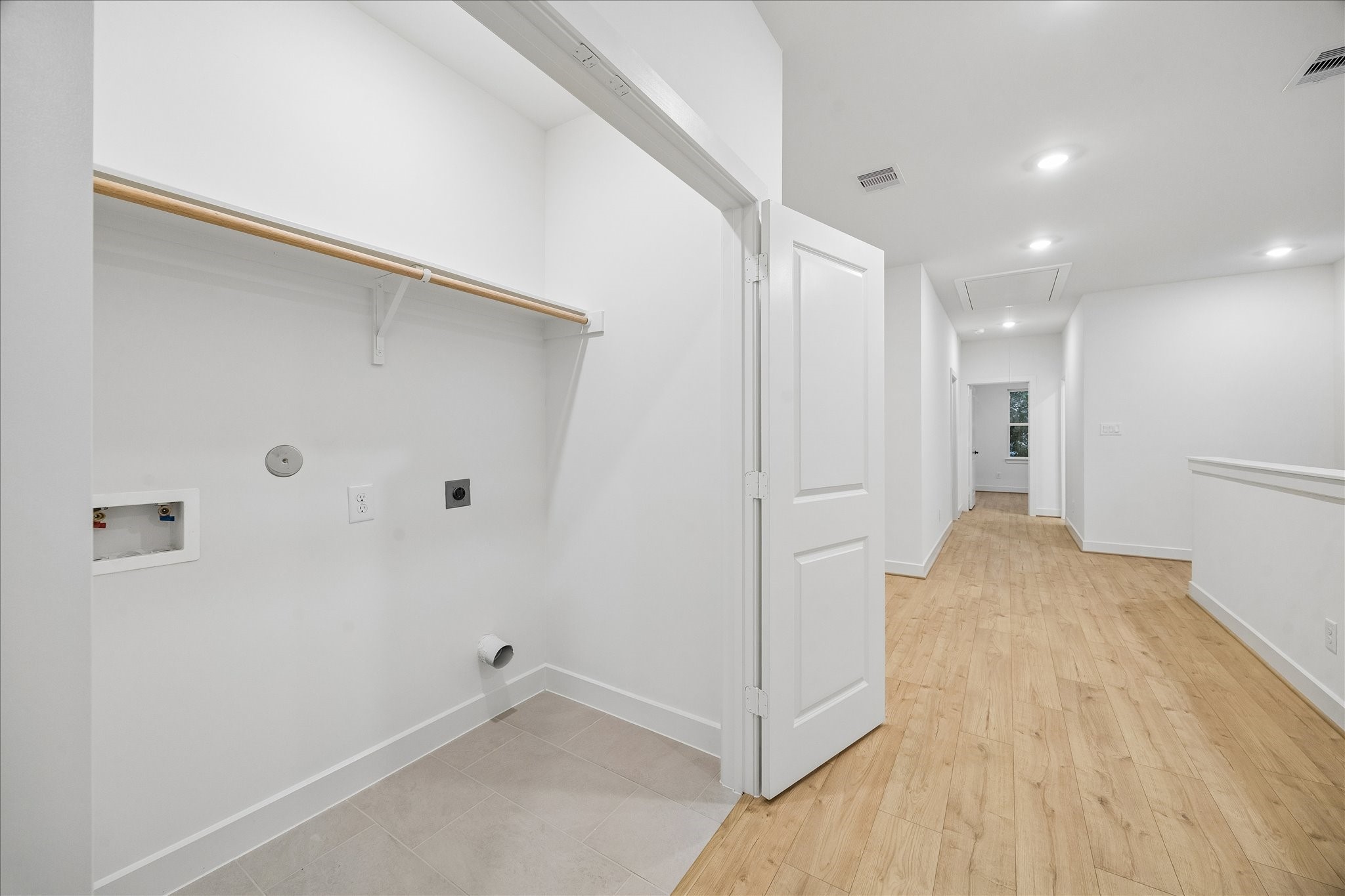 Convenient upstairs laundry room with built-in shelving and washer/dryer connections, located near the bedrooms for easy access.