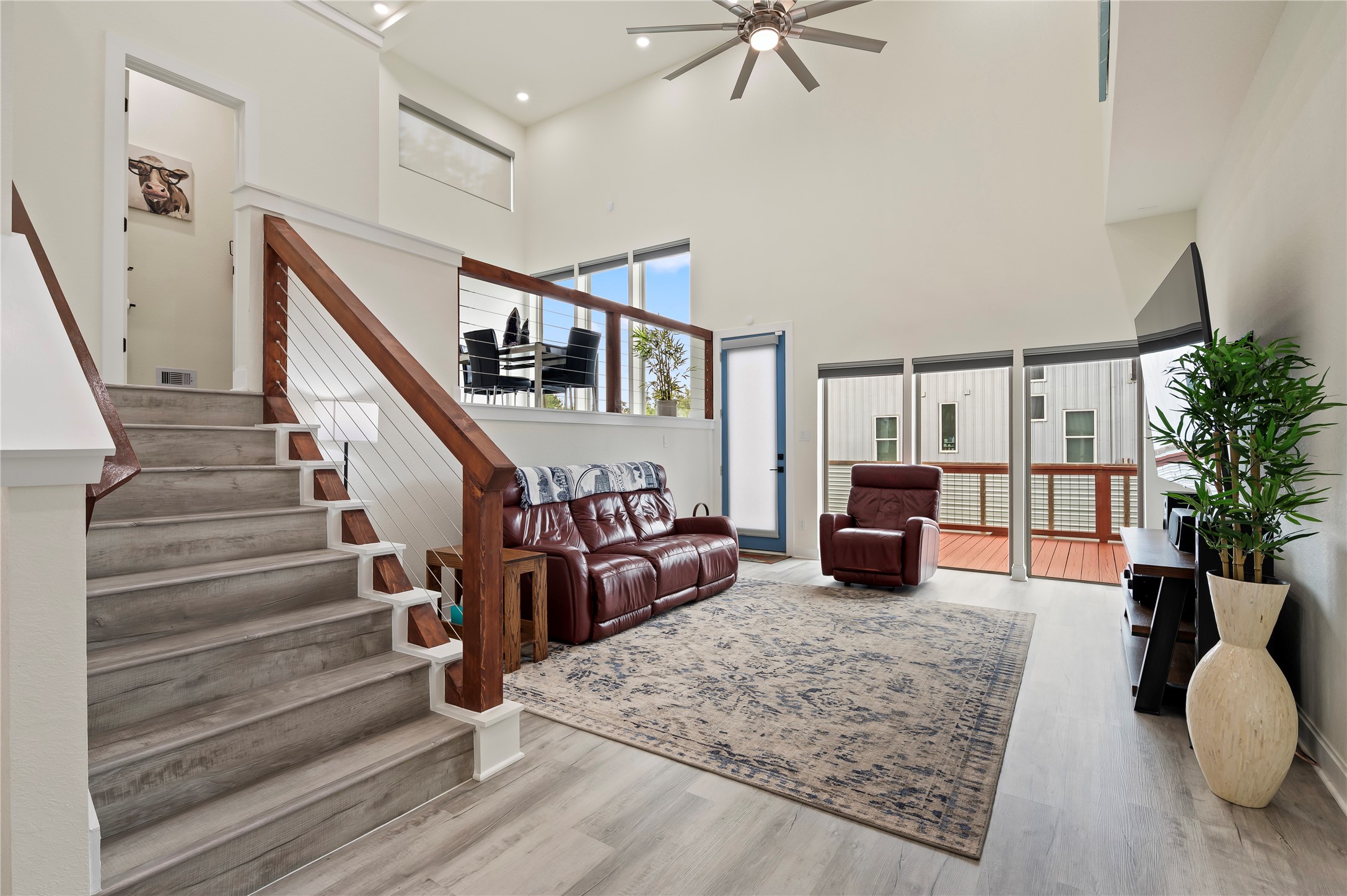 Spacious living room features high ceilings spans 20-feet high, COREtec Pro Plus Vinyl Plank in Chesapeake Oak and upscale dual directional up/down blinds, lowered from the top and raised from the bottom simultaneously or separately.