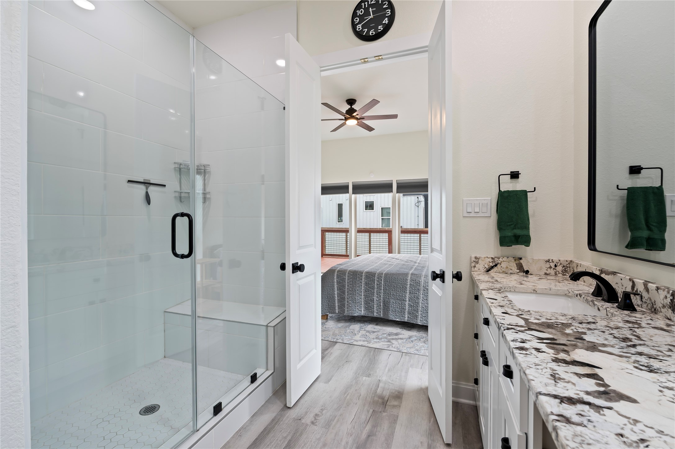 Oversized walk-in glass shower with seating bench and White Porcelain tile surrounding with honeycomb flooring.