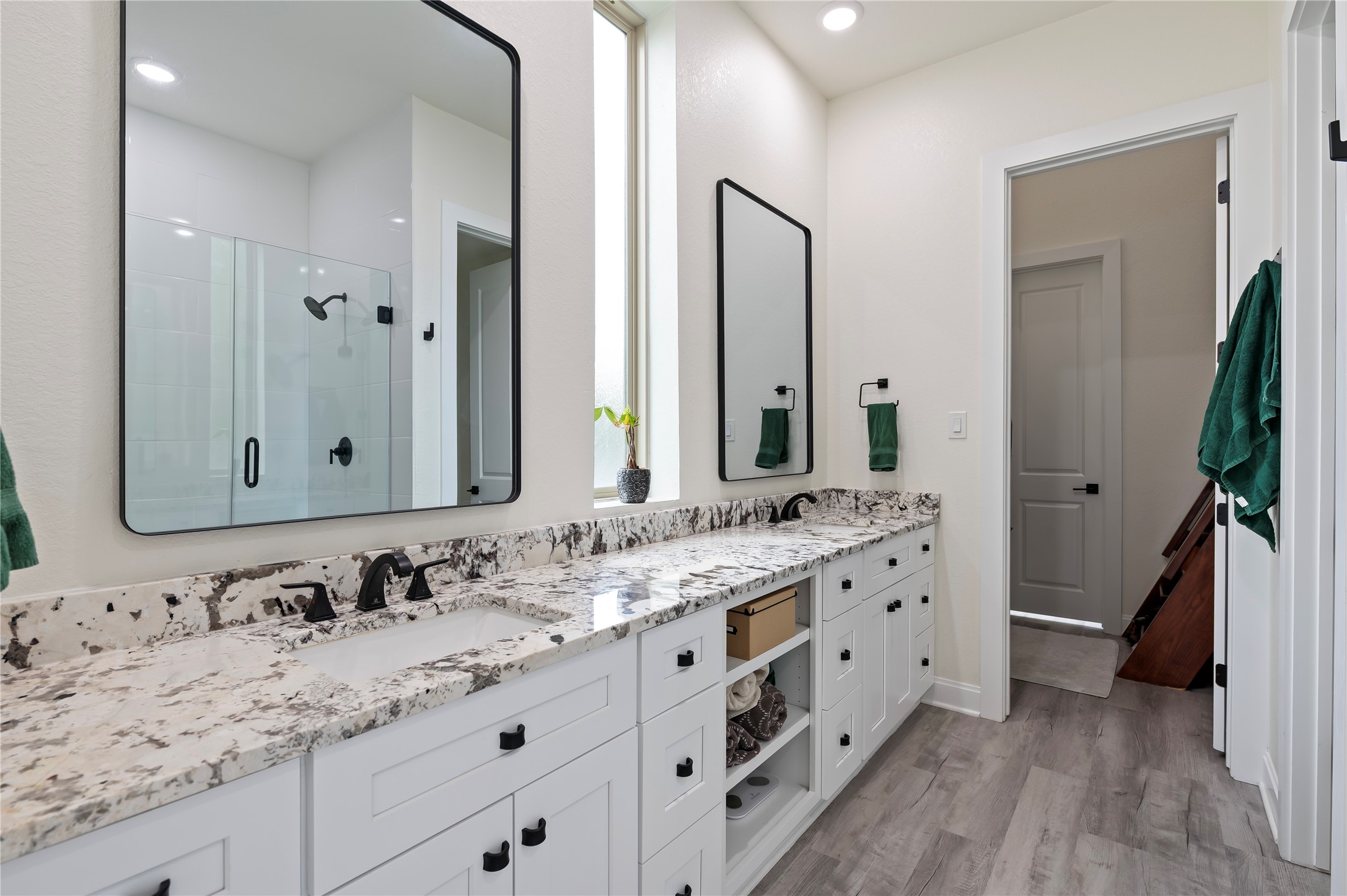 Gorgeous primary bathroom features Alaskan White Granite countertops with custom hardware, ample storage drawers and shelves, dual vanities and 3 custom mirrors.