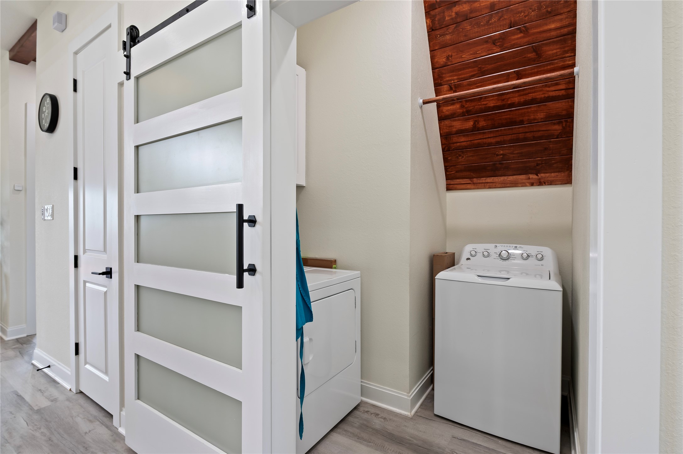 Full size laundry closet with modern sliding barn door, storage cabinet and cedar plank accent wall.