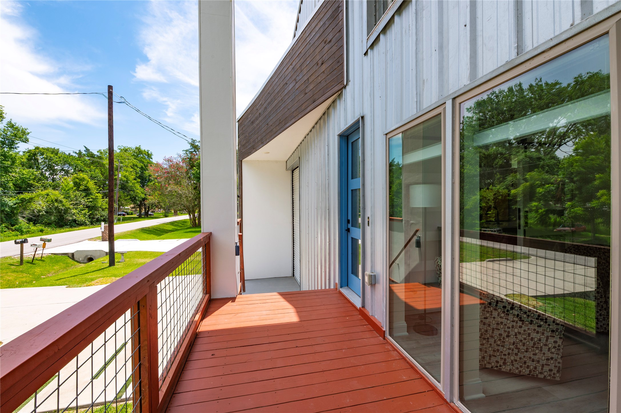 Oversized covered front porch decking features 3/4" conduit horizontal railing and dusk to dawn step accent lights. 8'x20' stained wood accent wall framing the garage.