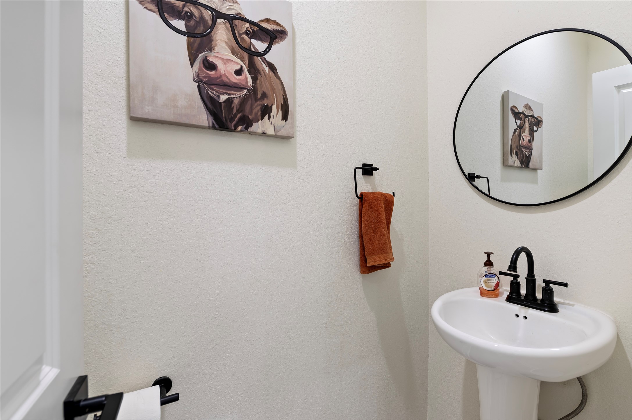 Convenient downstairs power room for guests featuring pedestal sink, framed mirror and COREtec Pro Plus Vinyl Plank flooring in Chesapeake Oak.