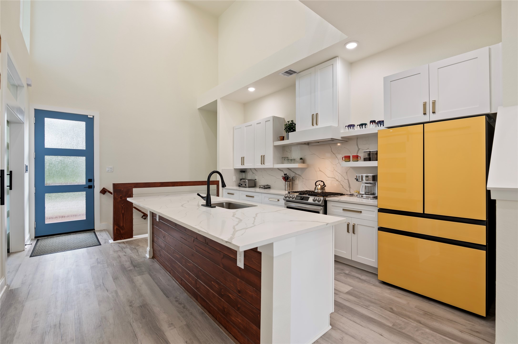 Stunning Quartz kitchen island with cedar plank accent wall. Stainless steel Samsung Bespoke Dishwasher and Gas Range; side by side Refrigerator.